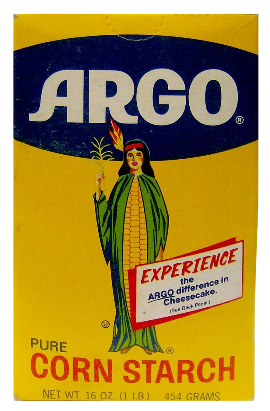 A vintage package of Argo pure corn starch with a yellow background featuring a woman dressed as a Native American with a feathered headdress, holding a feather in one hand, and a label that says "Experience the Argo difference in cheesecake."
