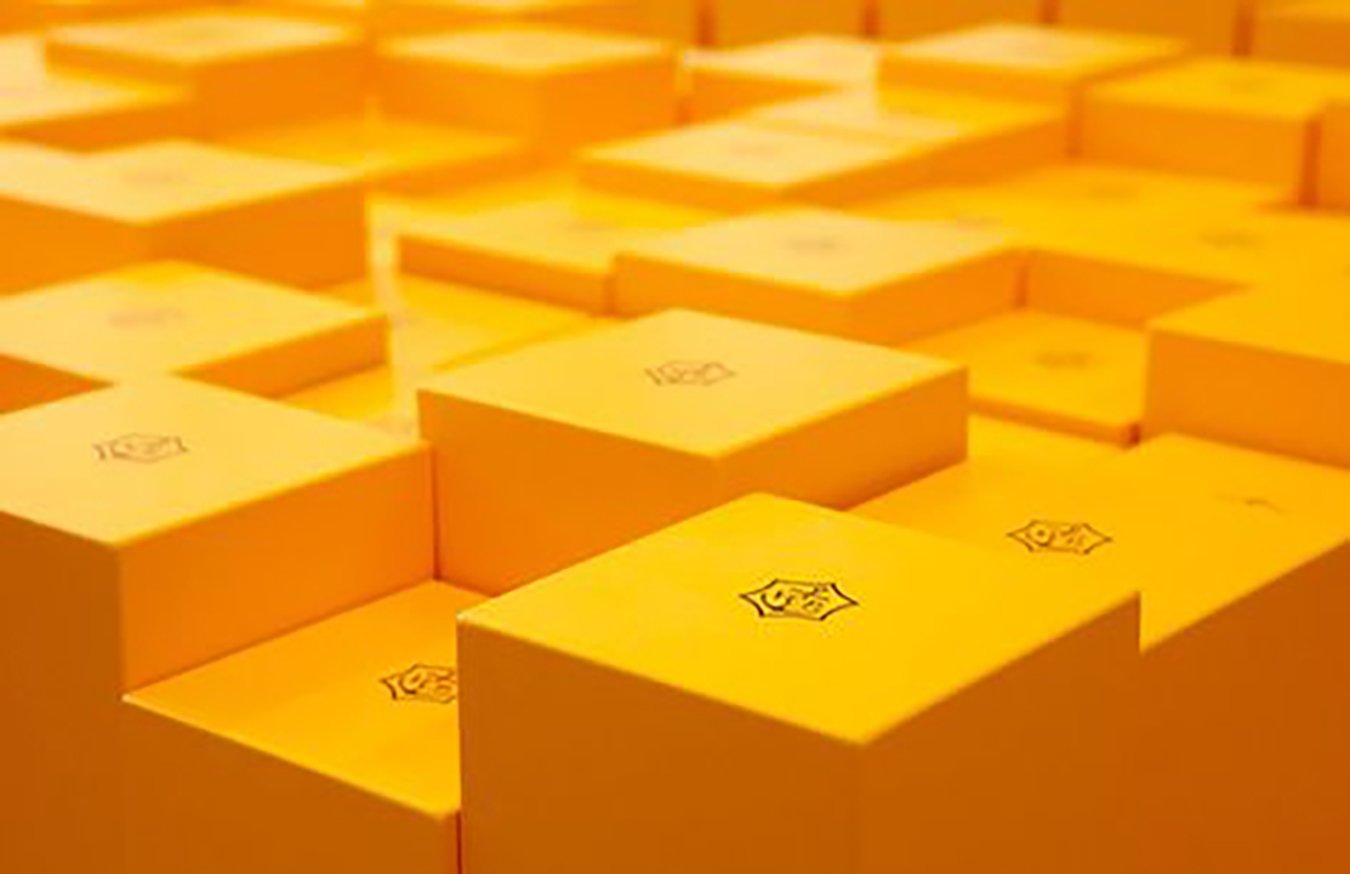 Multiple yellow boxes stacked in an organized grid pattern with a logo printed on the top of each box.