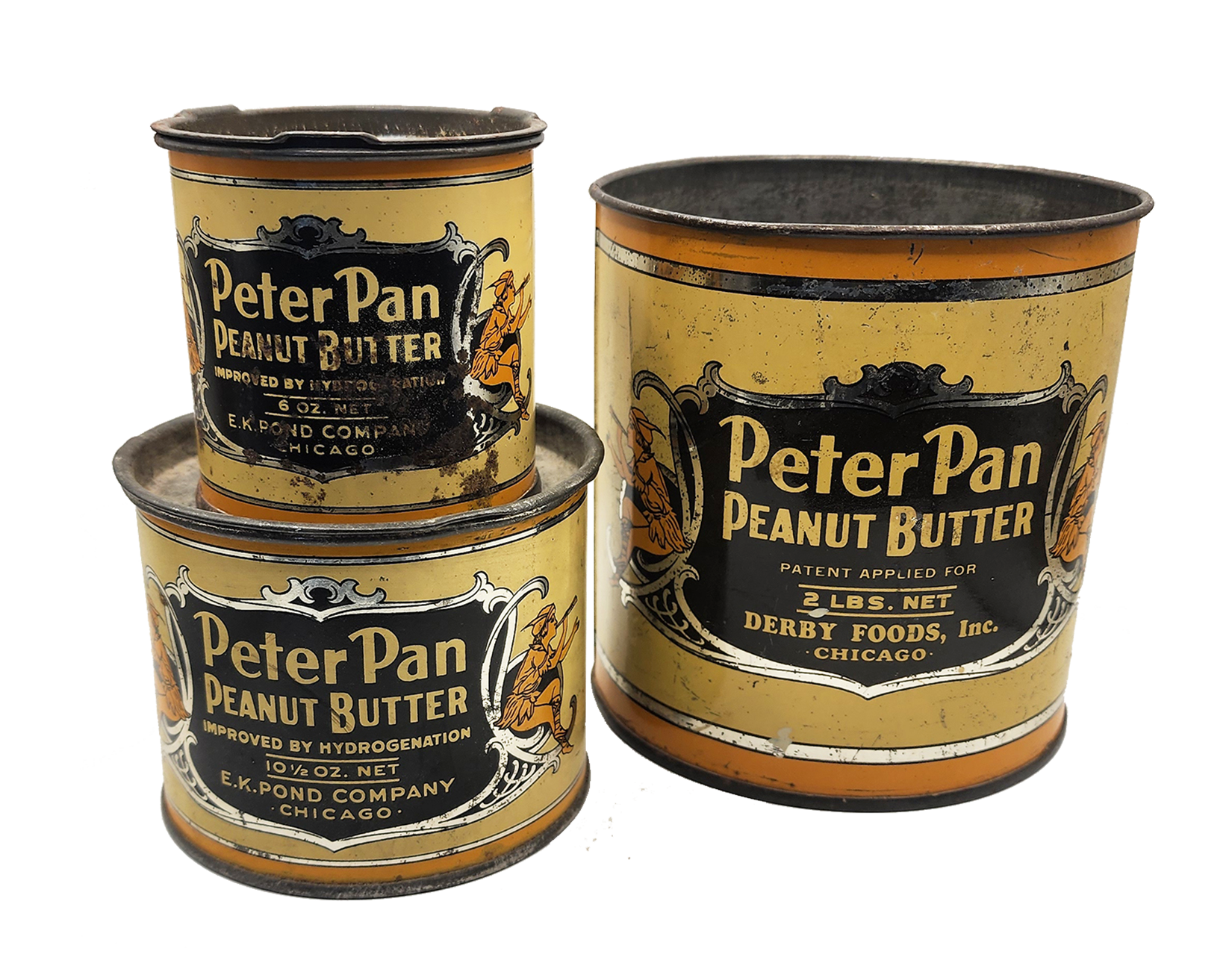 Three vintage cans of Peter Pan Peanut Butter, with beige and black labels, showing an illustration of a woman sitting and the product name, one can is open and the other two are closed.