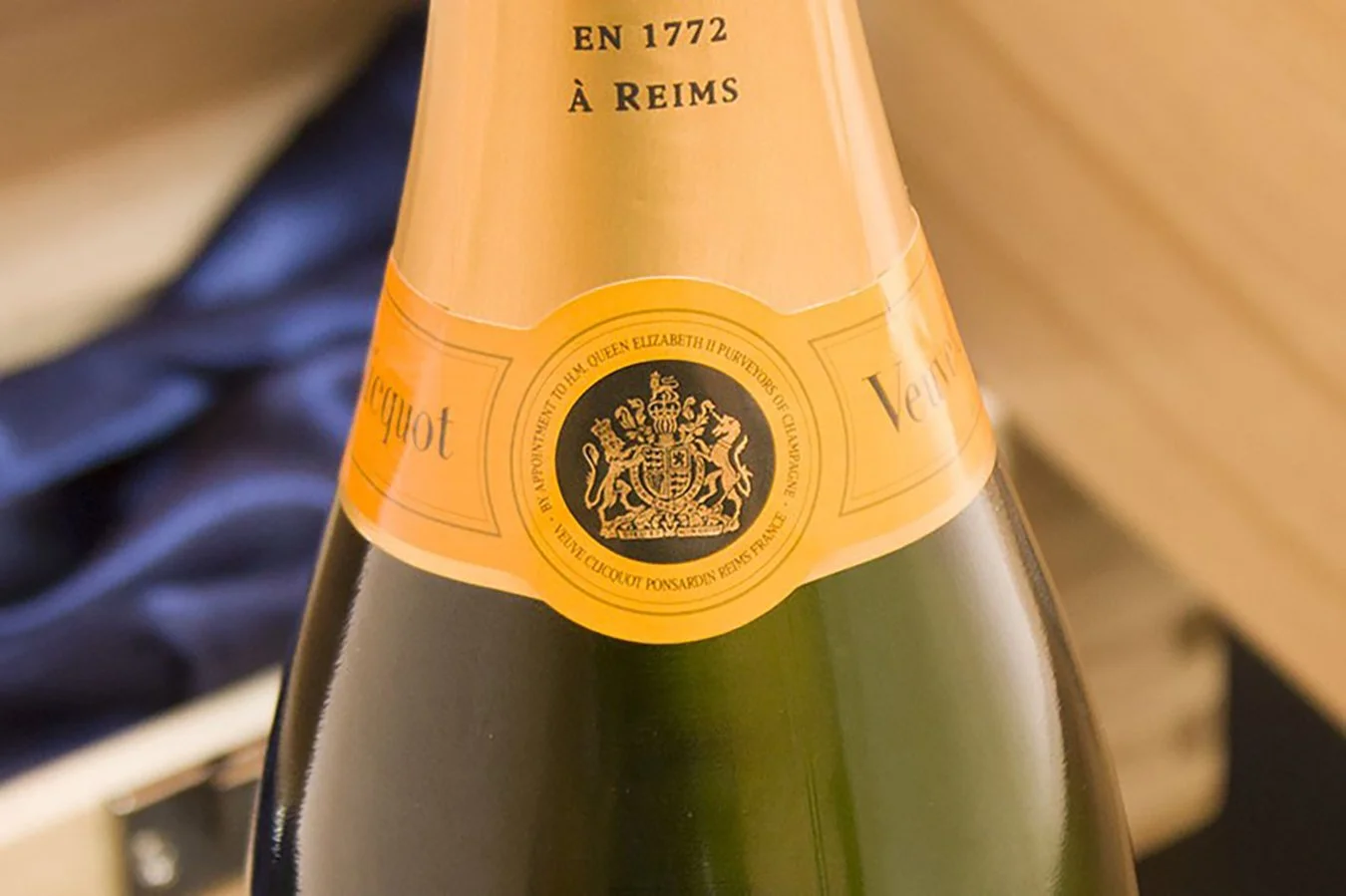 Close-up of a champagne bottle with a gold neck label that indicates it was made in Reims in 1772, featuring a crest with a crown and lions.