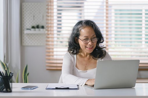 Elderly asian woman talking through Squarespace web designer through videoconference about her nonprofit business