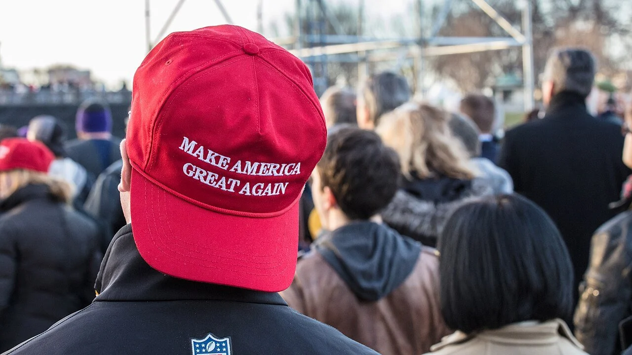 An American male wearing a backwards MAGA red baseball cap, his face obscured.