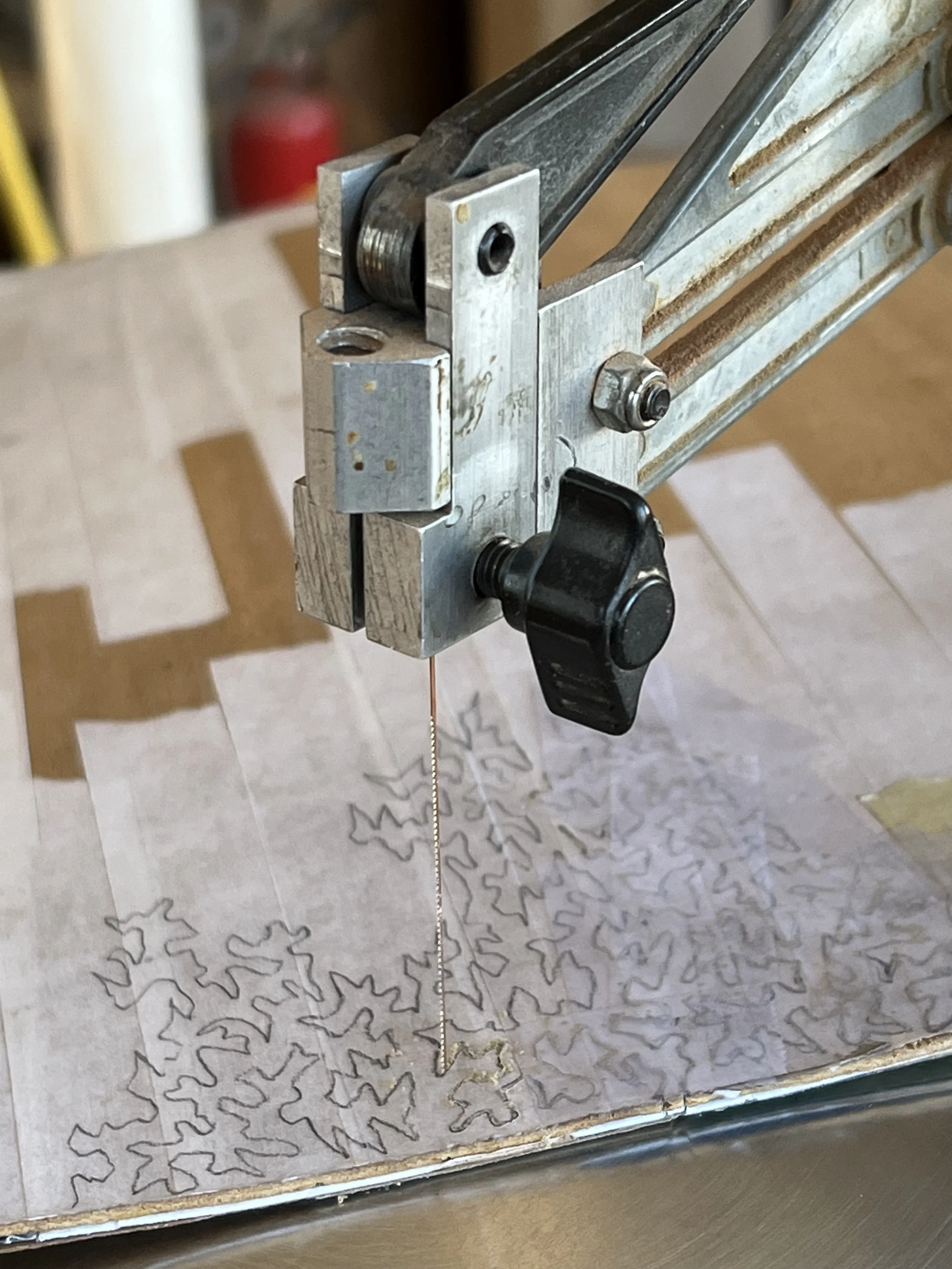 Close-up photo of the scroll saw in the process of cutting the foliage pattern into some veneer