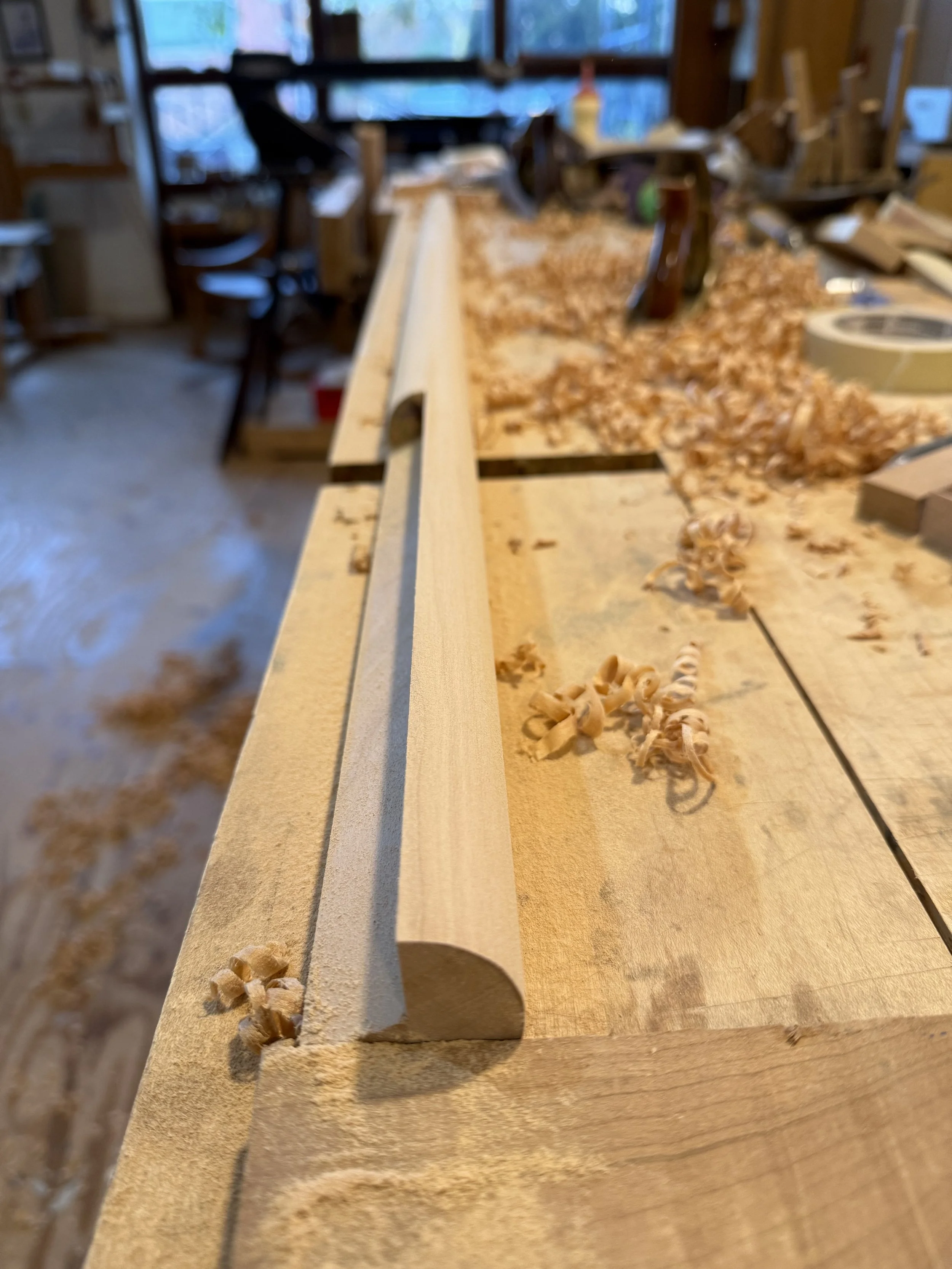 Photograph of one of the cabinet legs on the workbench with lots of wood shavings around it