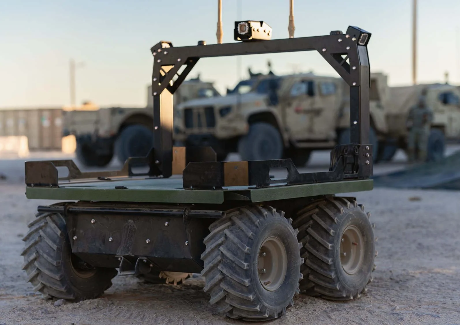 Stridar Siderunner UAV in front of military vehicles in a desert environment.