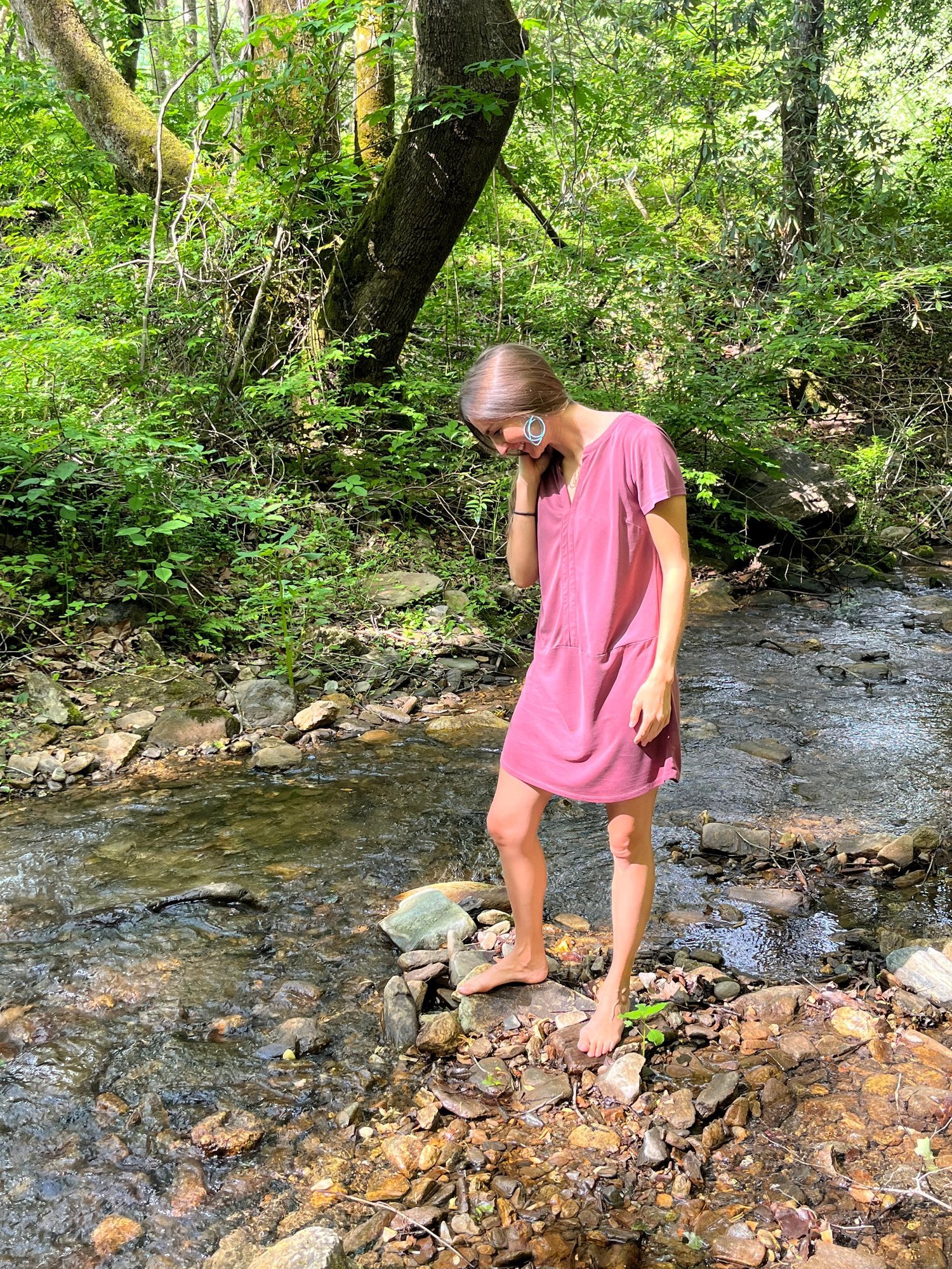 A woman pausing in a creek — listening to what her body is asking for