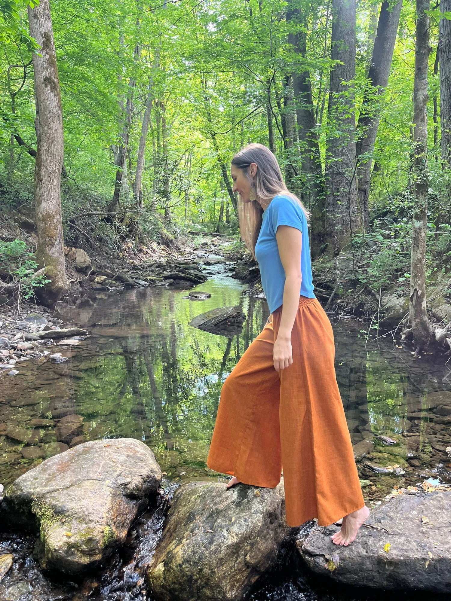 Alex Rice stepping across creek stones — beginning the personalized Ayurvedic cleanse journey