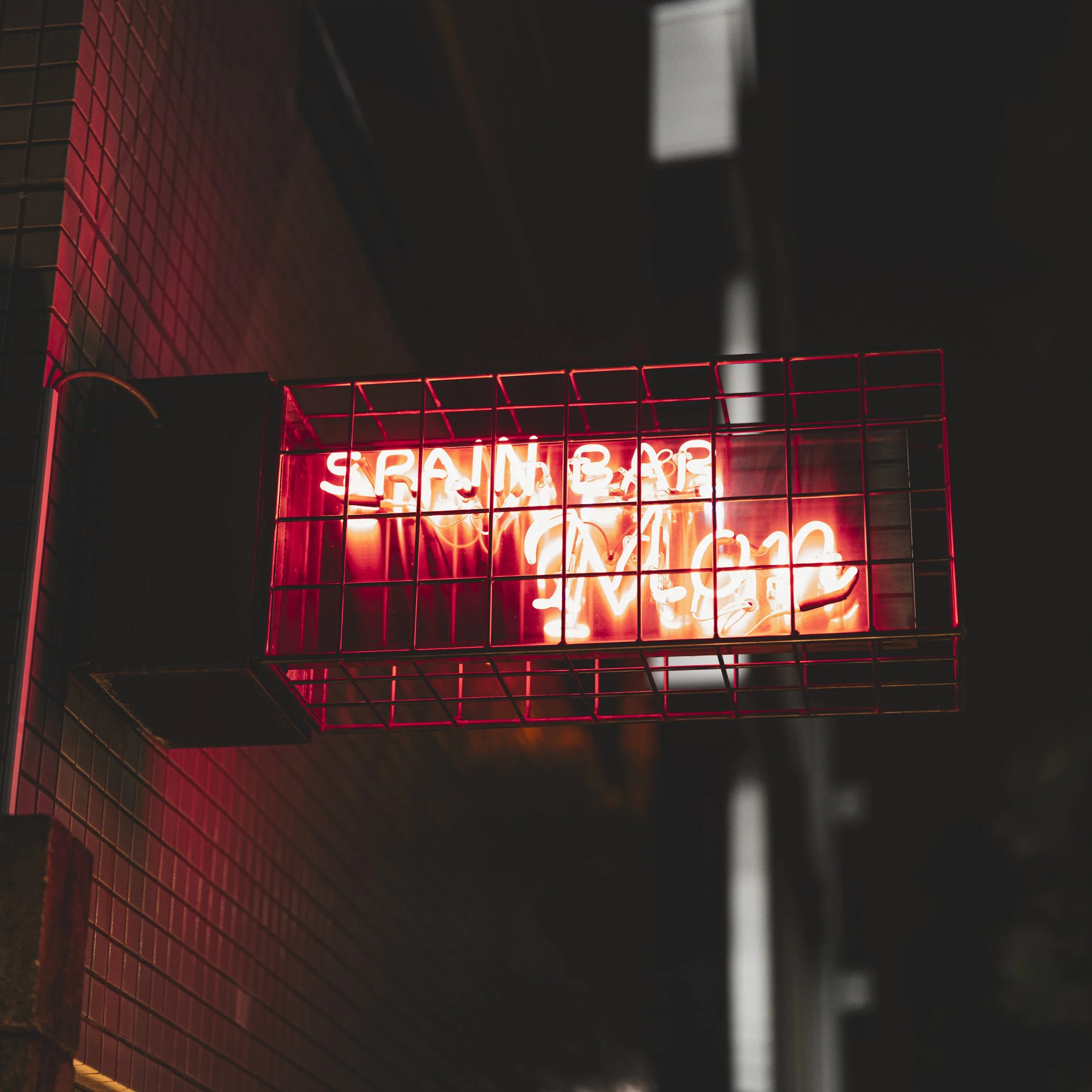 Neon sign on brick wall reads 'SRAIN BEACH MUSIC' in bright pink and white colors.