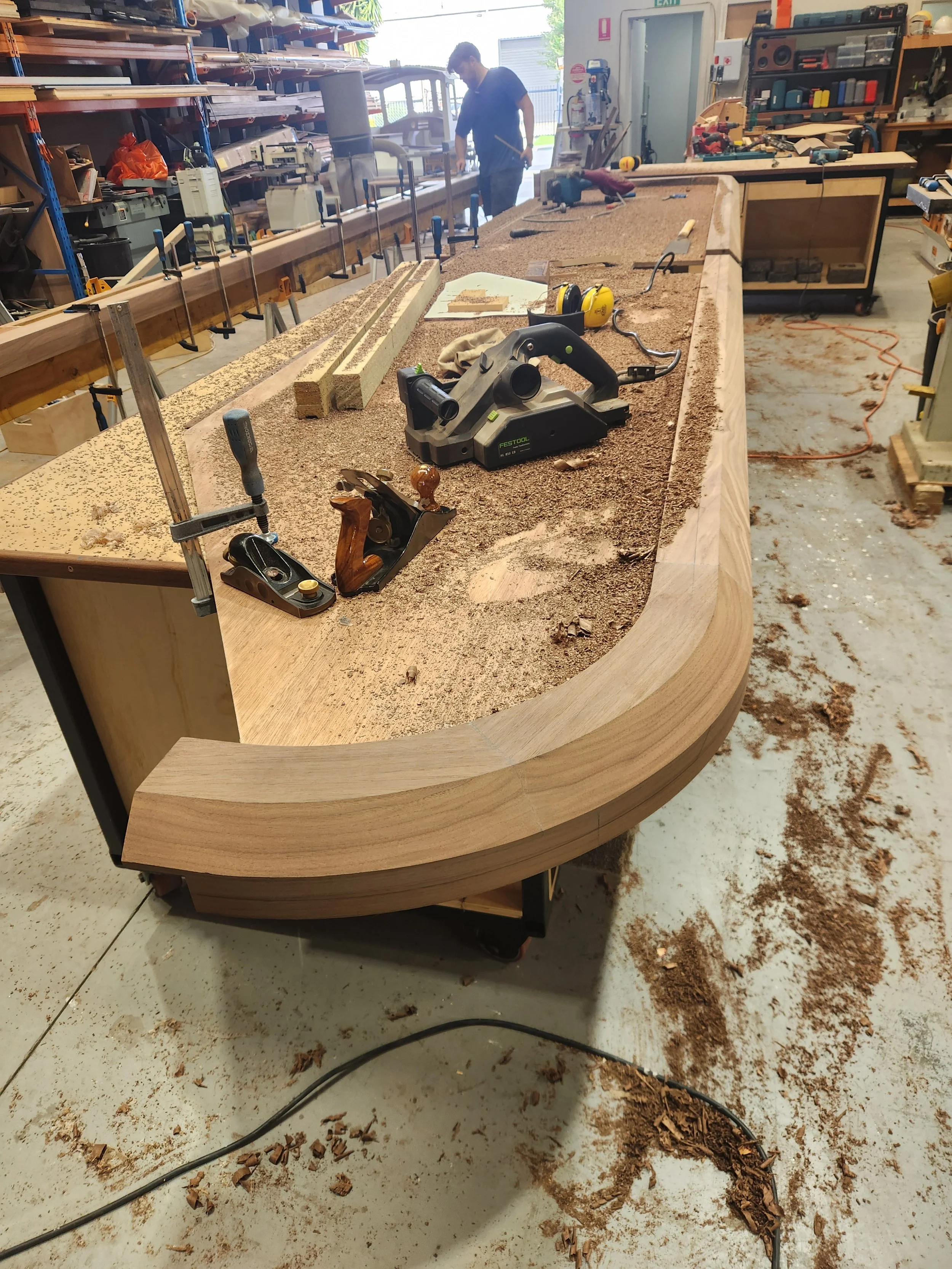 Hand shaping and carving custom Walnut timber bar edge.