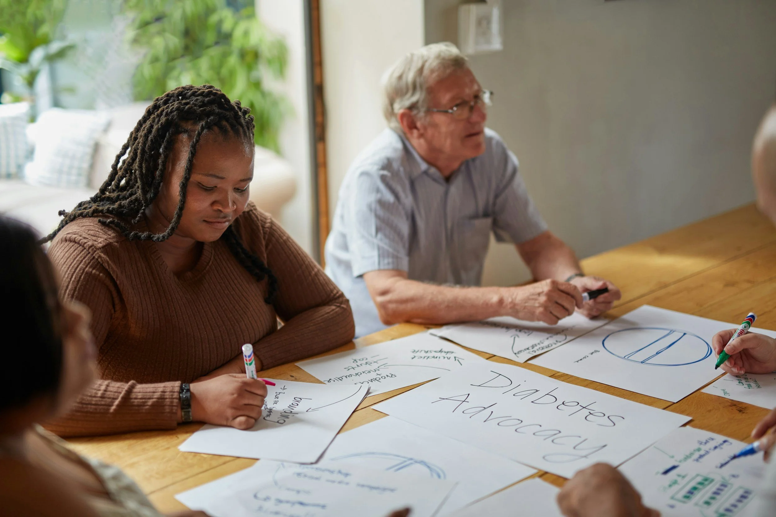 Group of people in a meeting room working on whiteboards with diagrams and notes.