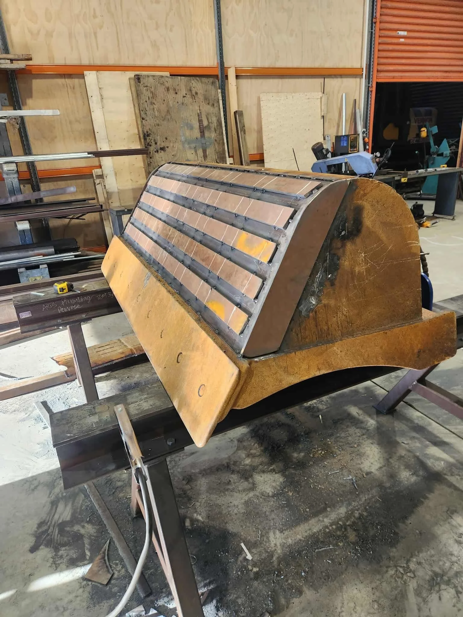 A digger bucket repair in progress on a workbench in a workshop.