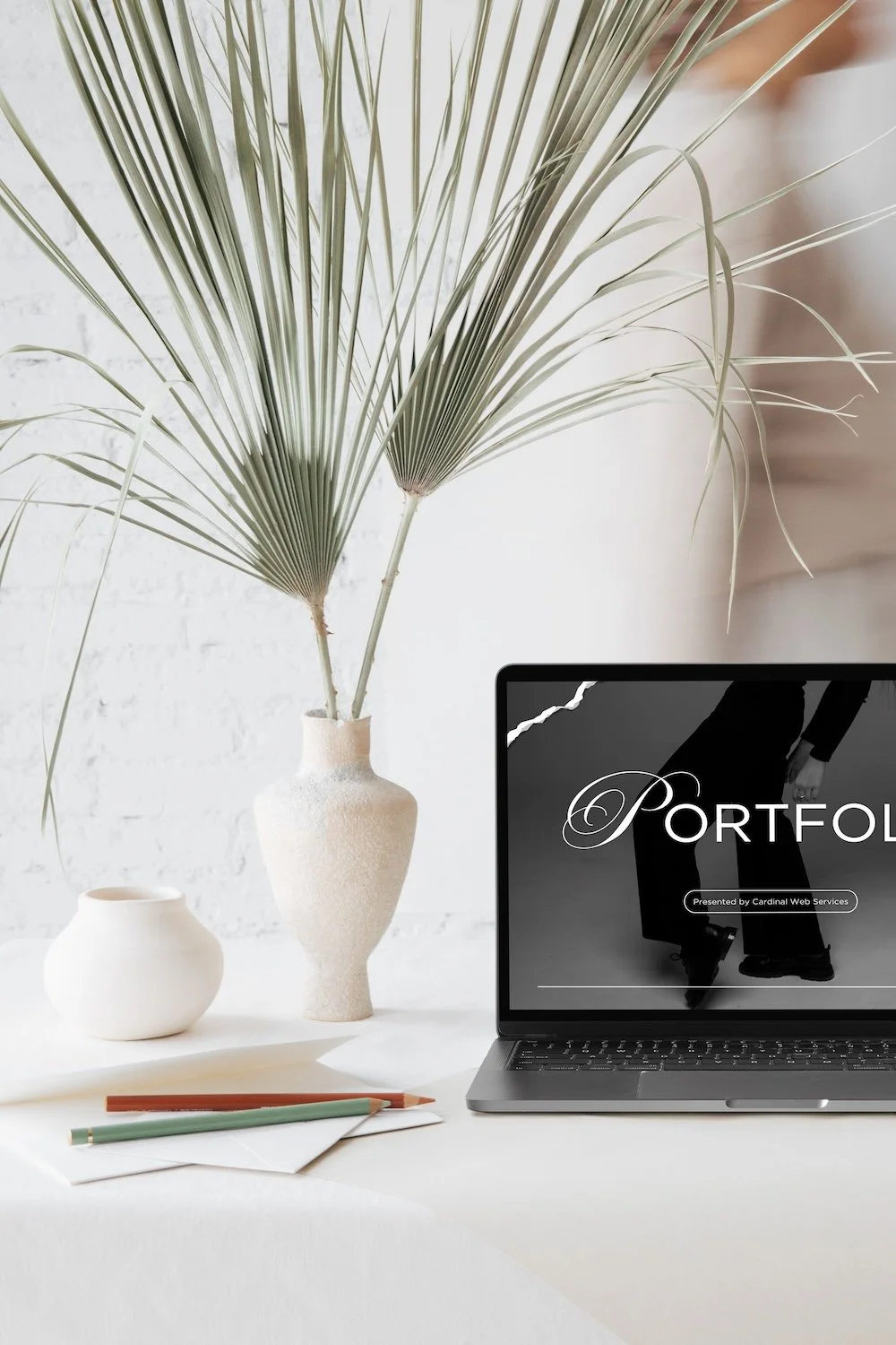 Portfolio website mockup displayed on a laptop beside neutral desk decor