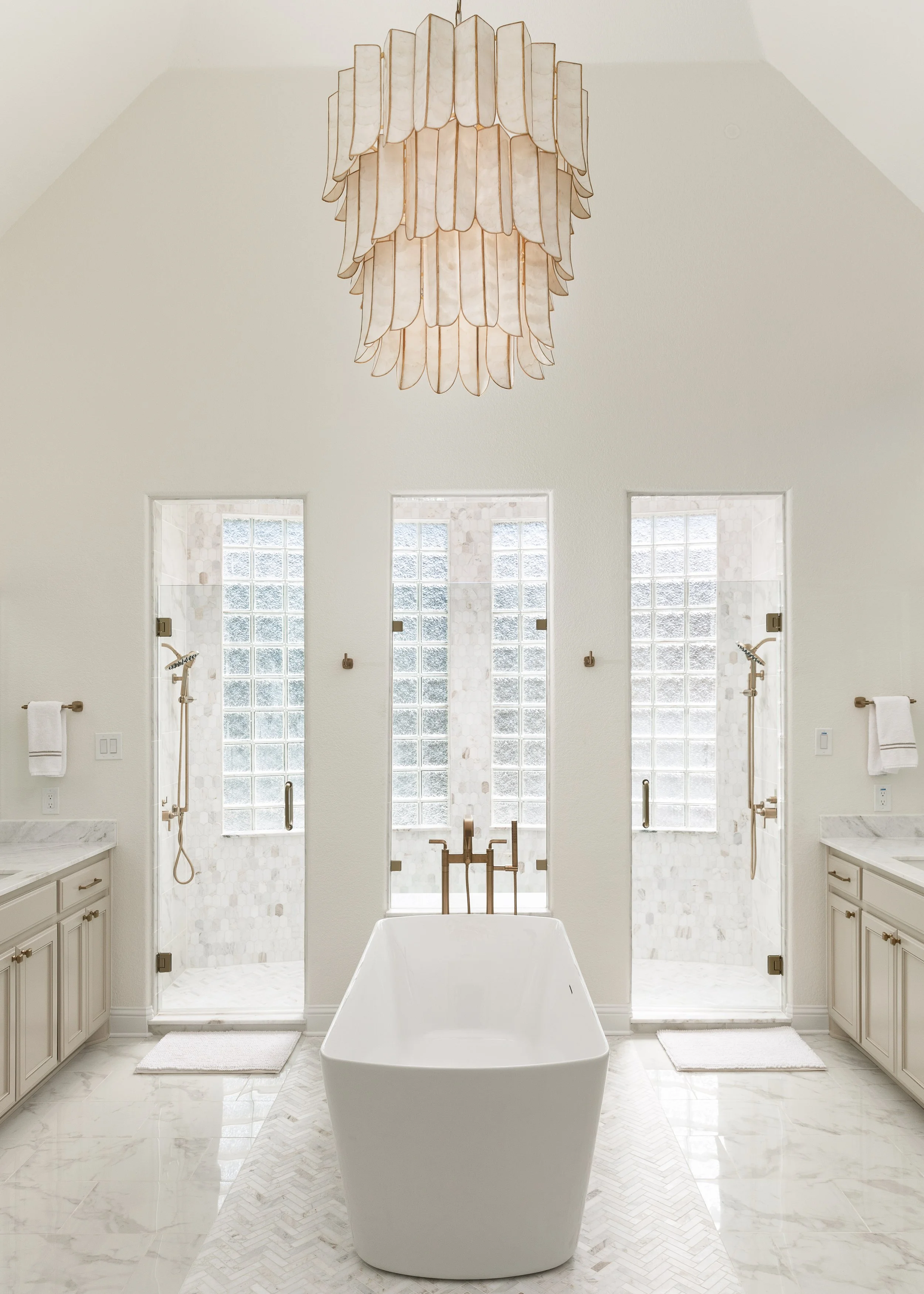 Modern bathroom with a standalone bathtub, two shower stalls with glass doors, and large windows, all in a bright and elegant design.