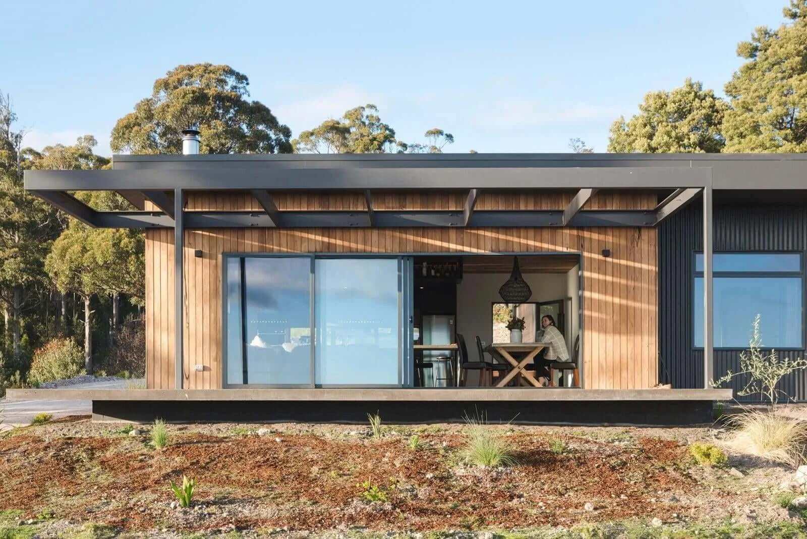 Rural dream home facade timber shiplap cladding, steel arbor, Colorbond Monument cladding and cantilevered deck in South Spreyton, Tasmania by Loubser Workshop