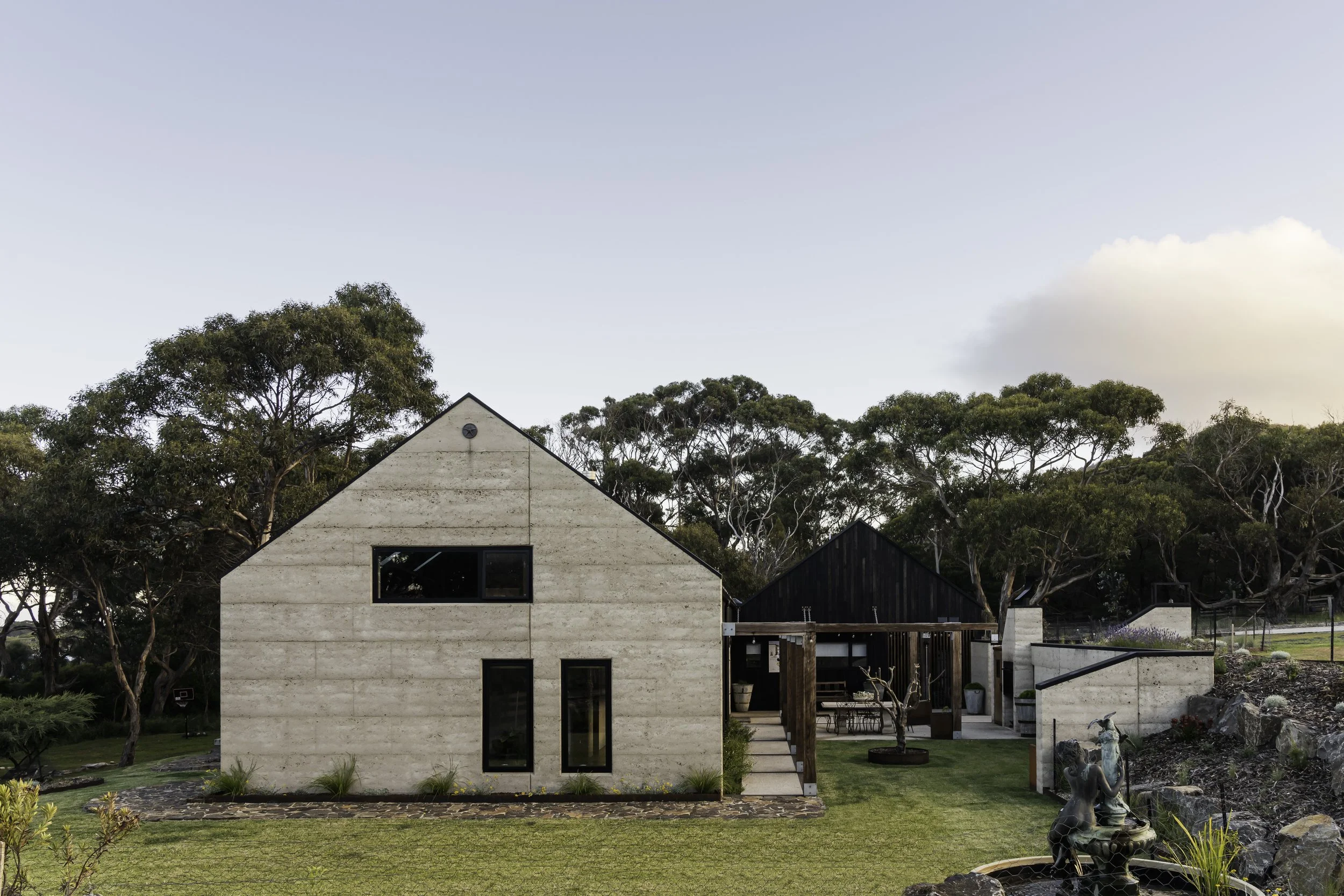Rural dream home facade with rammed earth, Shou Sugi Ban cladding and ironbark arbor in Bicheno, Tasmania by Loubser Workshop