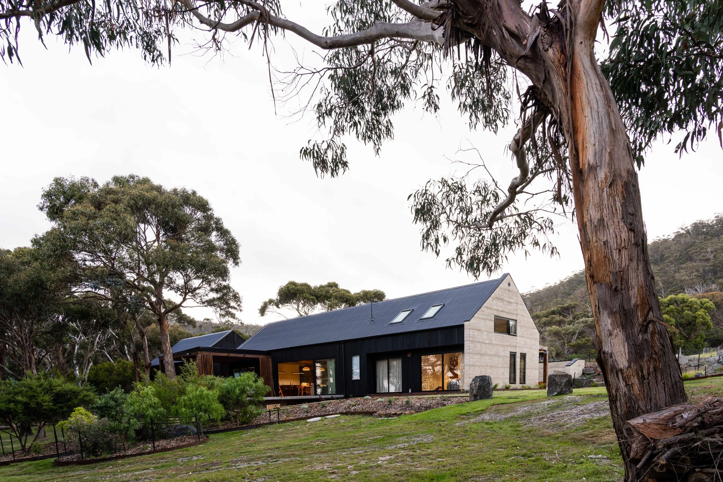 Rural dream home exterior with rammed earth, Shou Sugi Ban cladding in Bicheno, Tasmania by Loubser Workshop