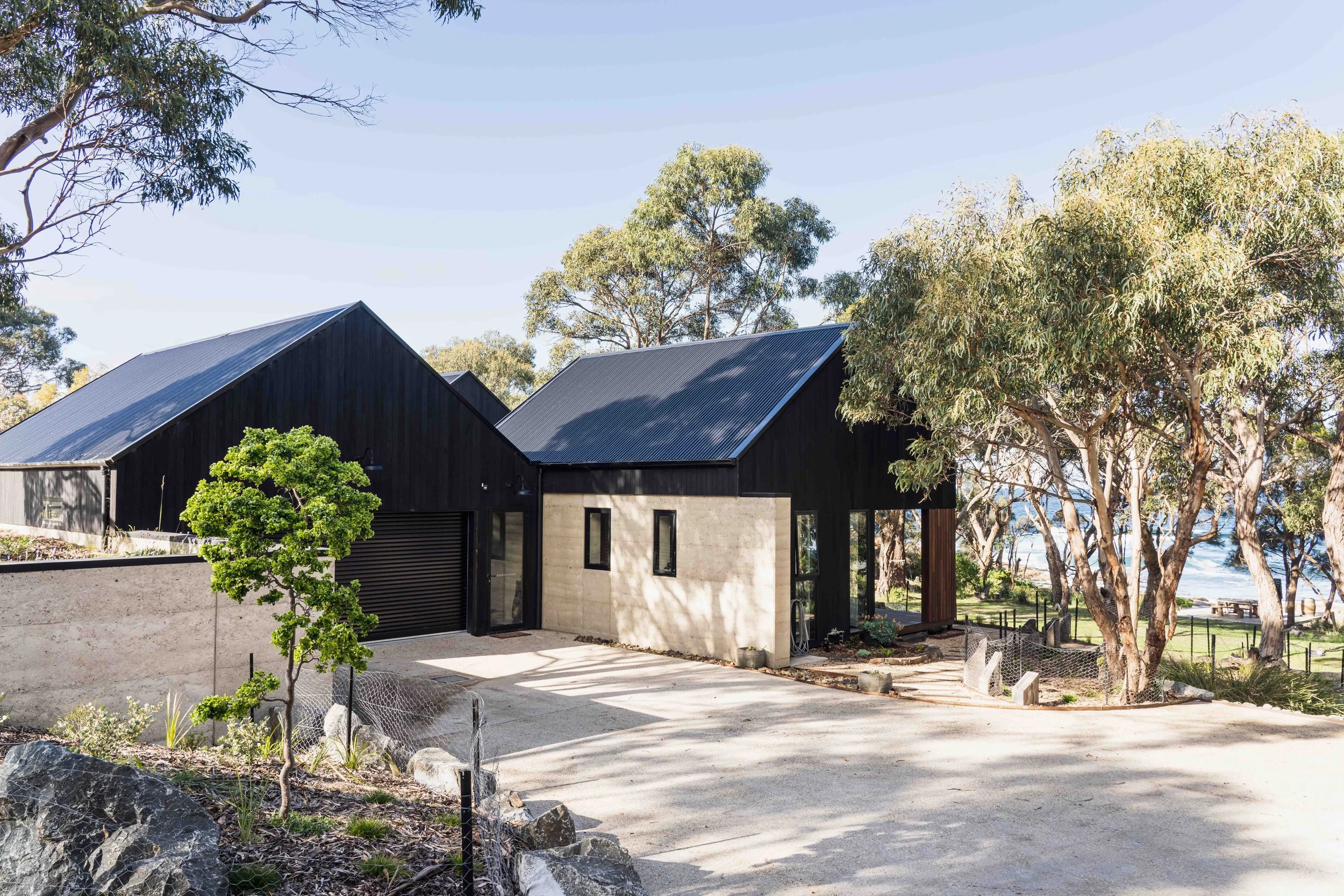 Rural dream home exposed aggregate driveway with rammed earth, Shou Sugi Ban cladding in Bicheno, Tasmania by Loubser Workshop