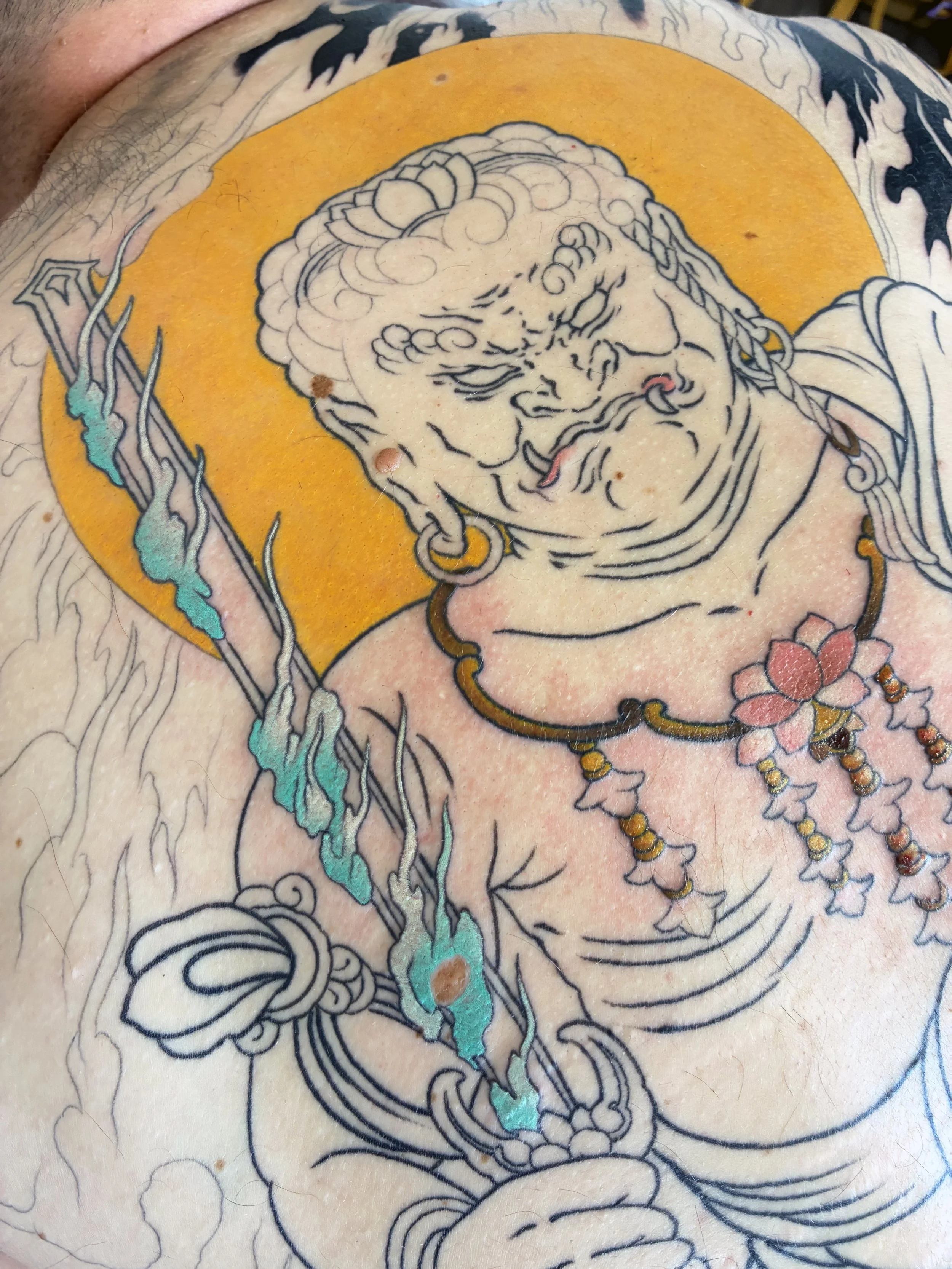 A close up in photo of this in progress Fudo Myoo Japanese back piece tattoo, colour in the halo is all healed and settled.