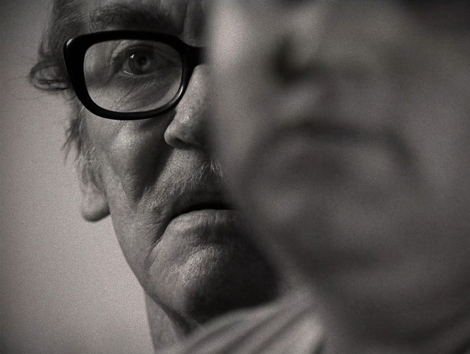 Close-up of two people's faces with one sharply in focus and the other blurred, showing facial features and glasses.