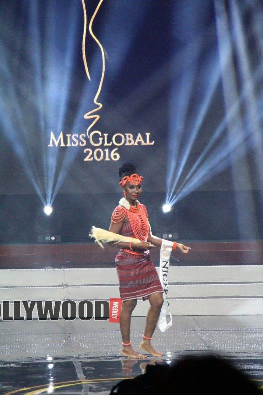 Miss Global 2016 contestant in traditional attire performing on stage at a pageant event.
