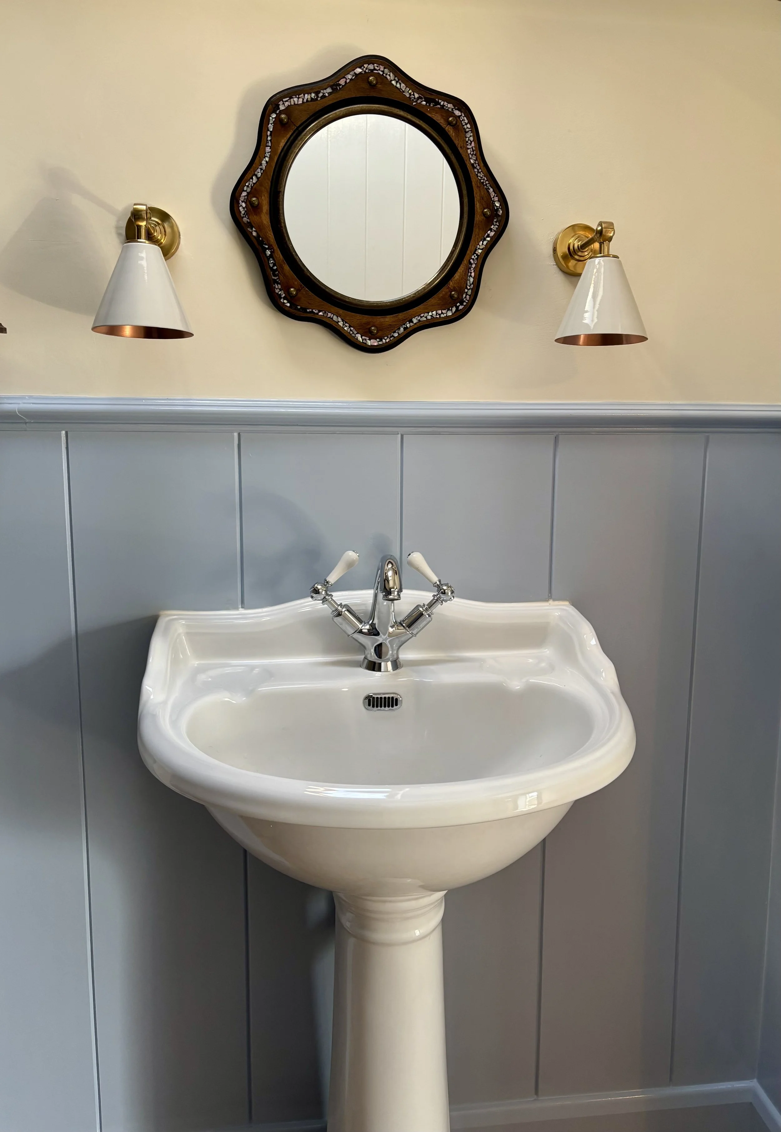 Sink, wall lights and mirror with blue panelling
