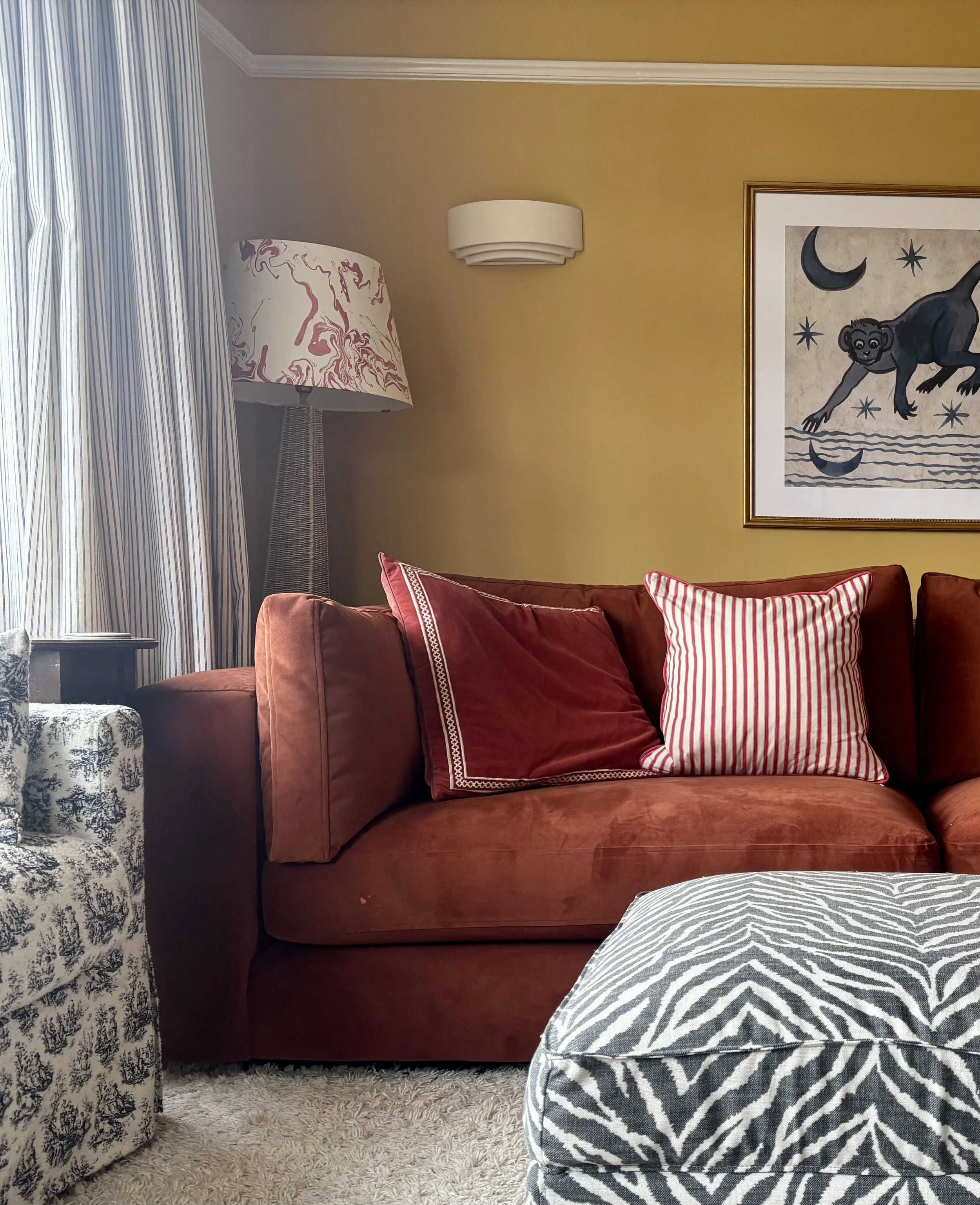 Living room with yellow walls, red sofa and zebra print ottoman