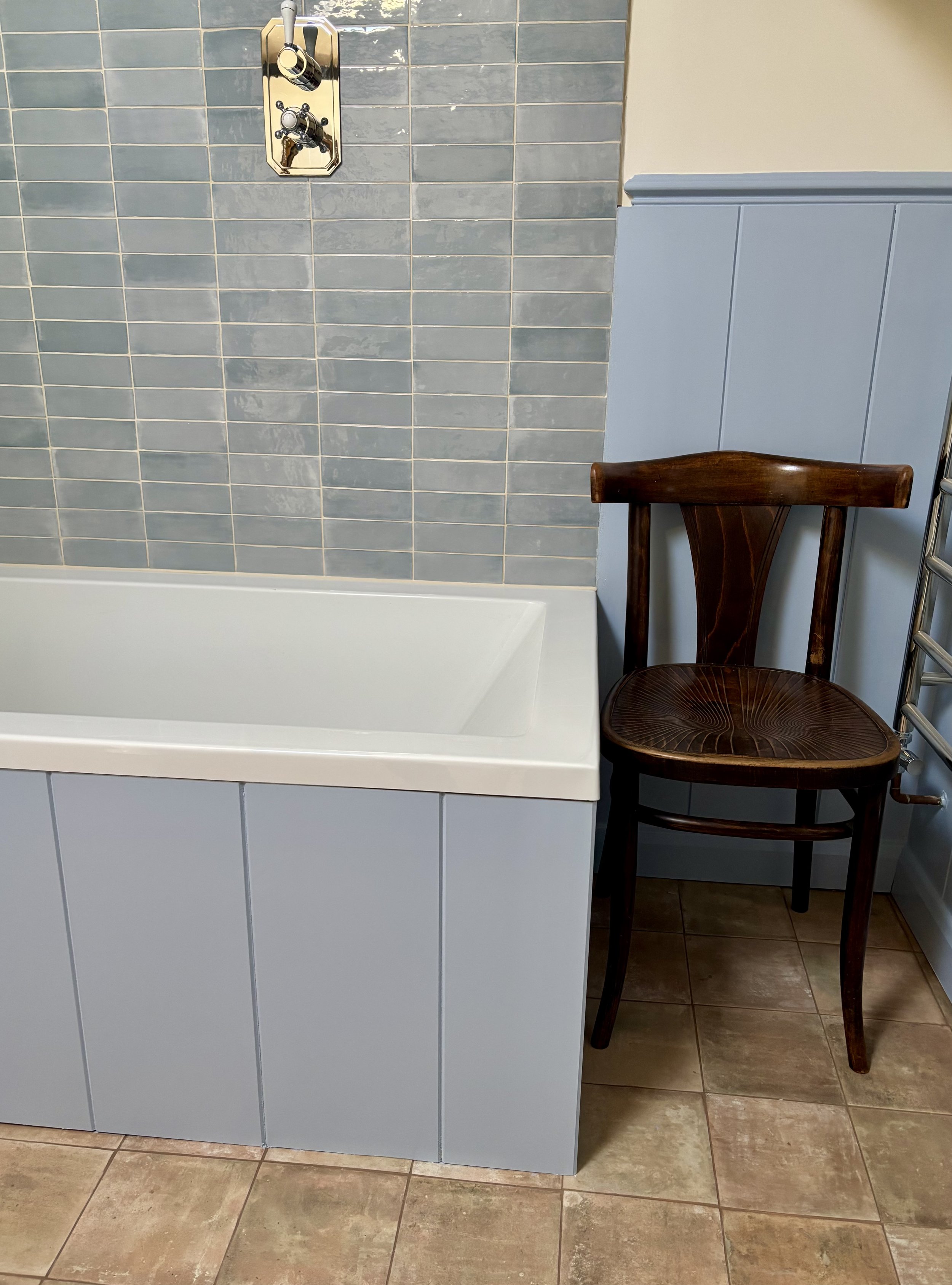Bath with blue tiles, with antique chair at the end