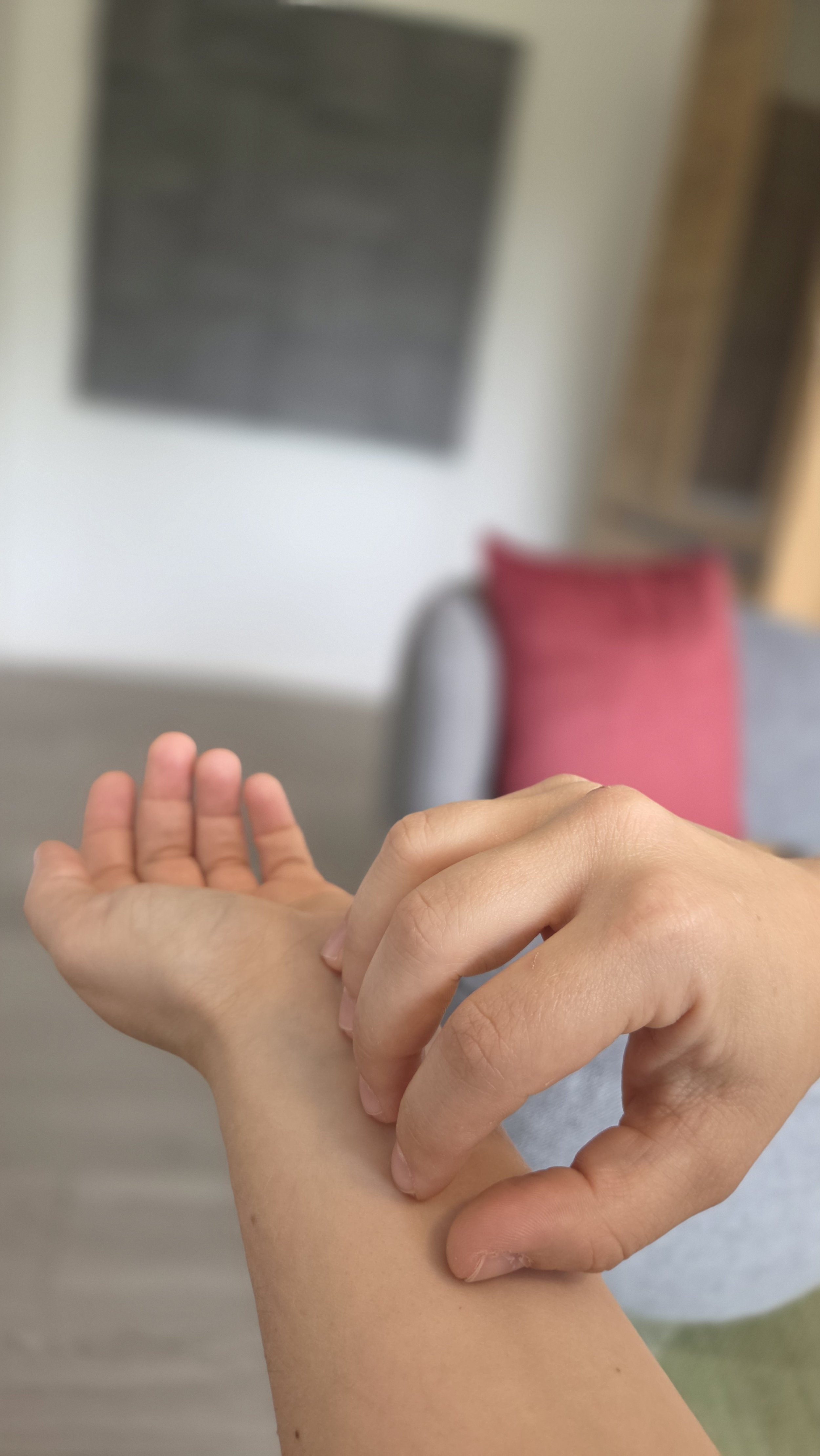 Eine Person, die sich am Handgelenk kratzt.