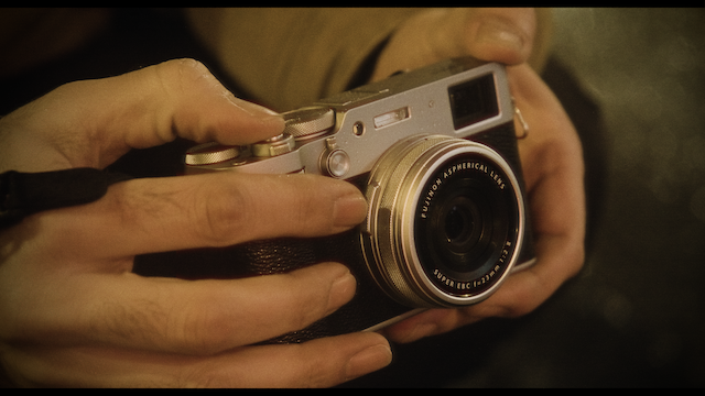 A detailed view of hands holding a classic silver and black camera, focusing on the intricacies and tactile qualities of the vintage-style device against a soft, blurred background.