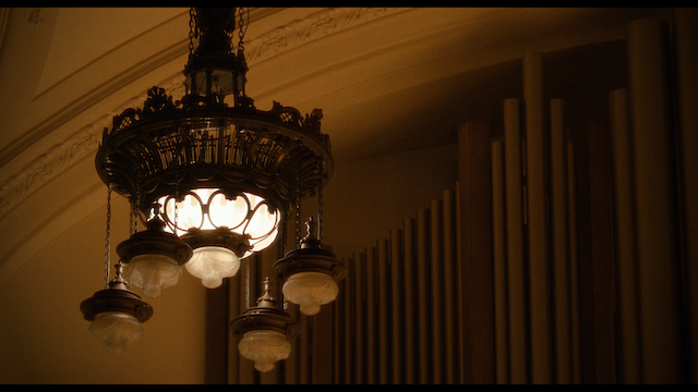 An ornate hanging chandelier in a vintage style, illuminating a classical venue with soft light, enhancing the architectural beauty of the space.