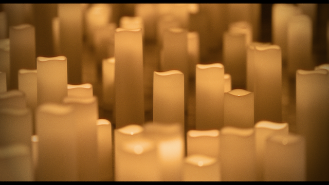 Close-up of many unlit candles with smooth, round tops, filling the frame to create a textured pattern of warm tones.