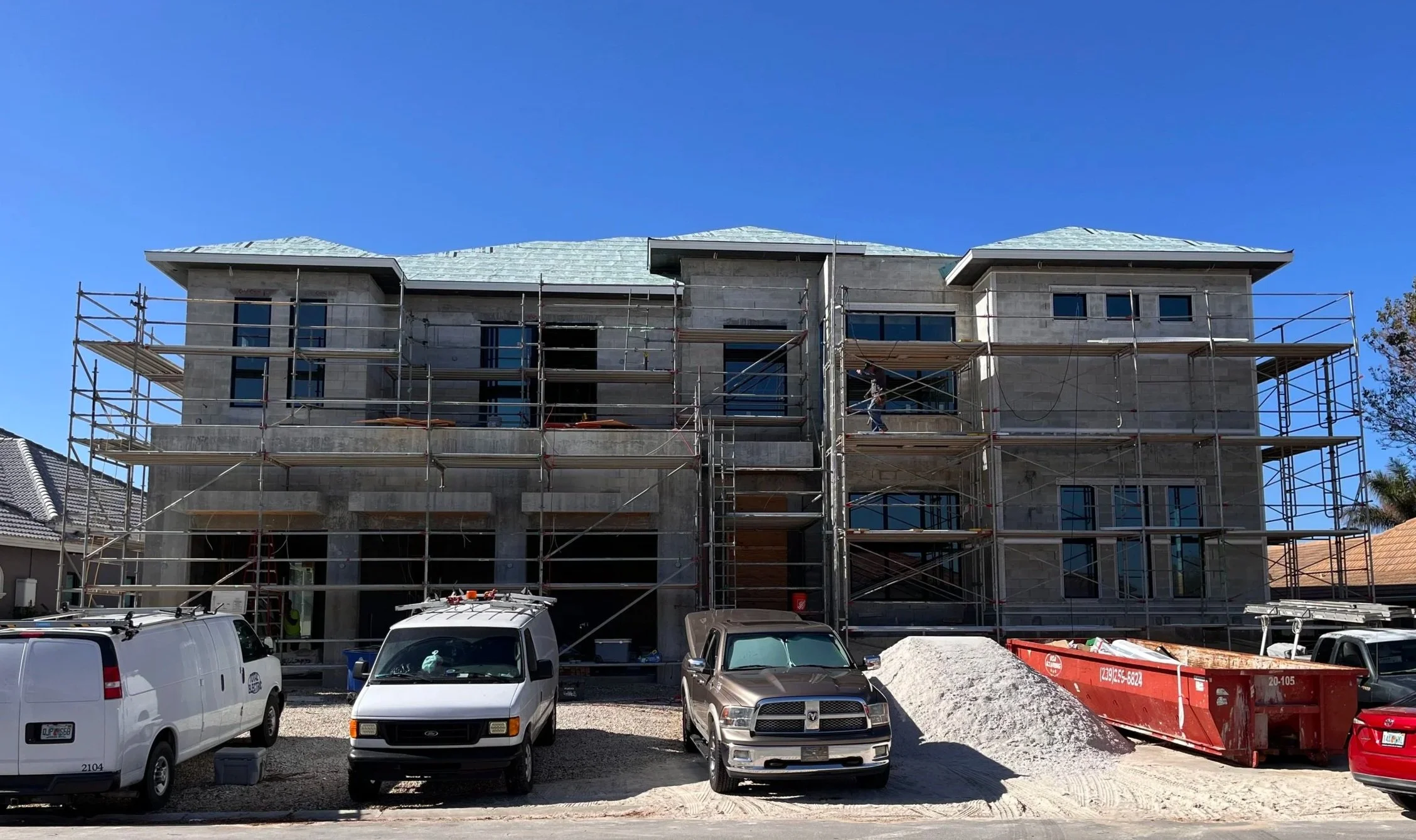 Construction of a multi-story building with scaffolding in preparation for lath and stucco work by Badger Builders Inc.