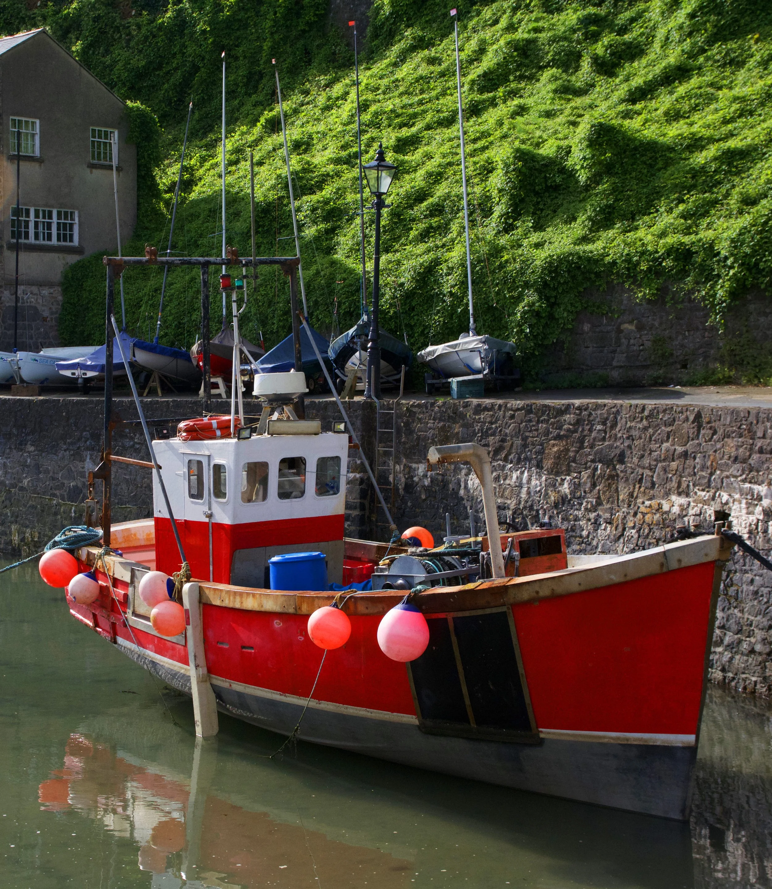Empty beachfront promenade with row of white buildings, cloudy blue sky, and cranes in the distance.