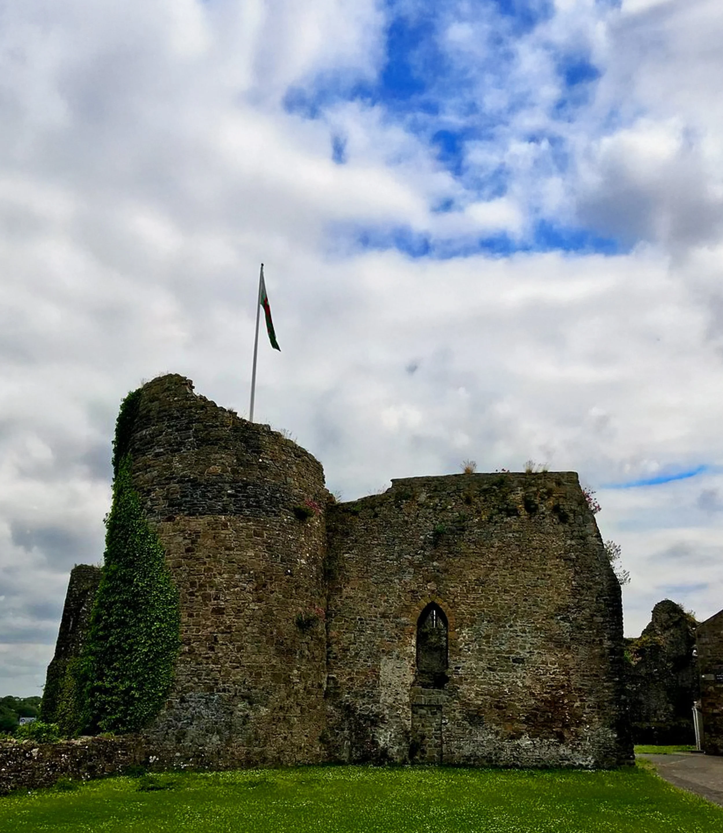 Aerial view of a historic castle and surrounding residential buildings in a small town, with lush green trees and construction in the background.