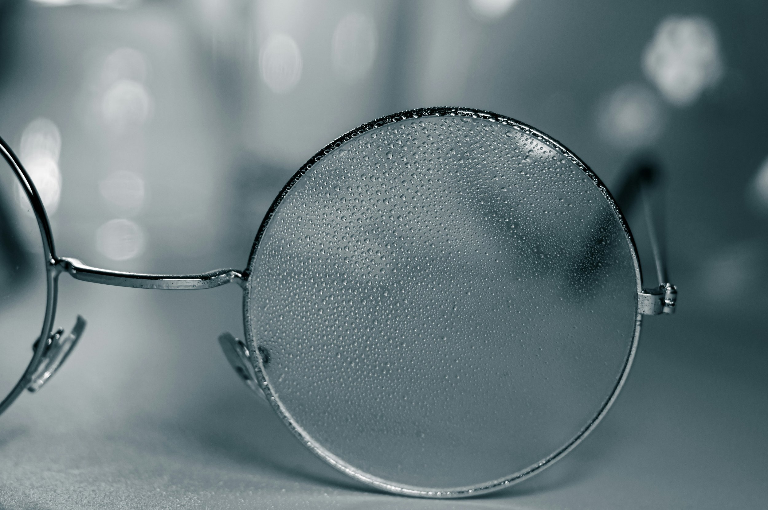 Round glasses, one of the glasses visible with small water drops.