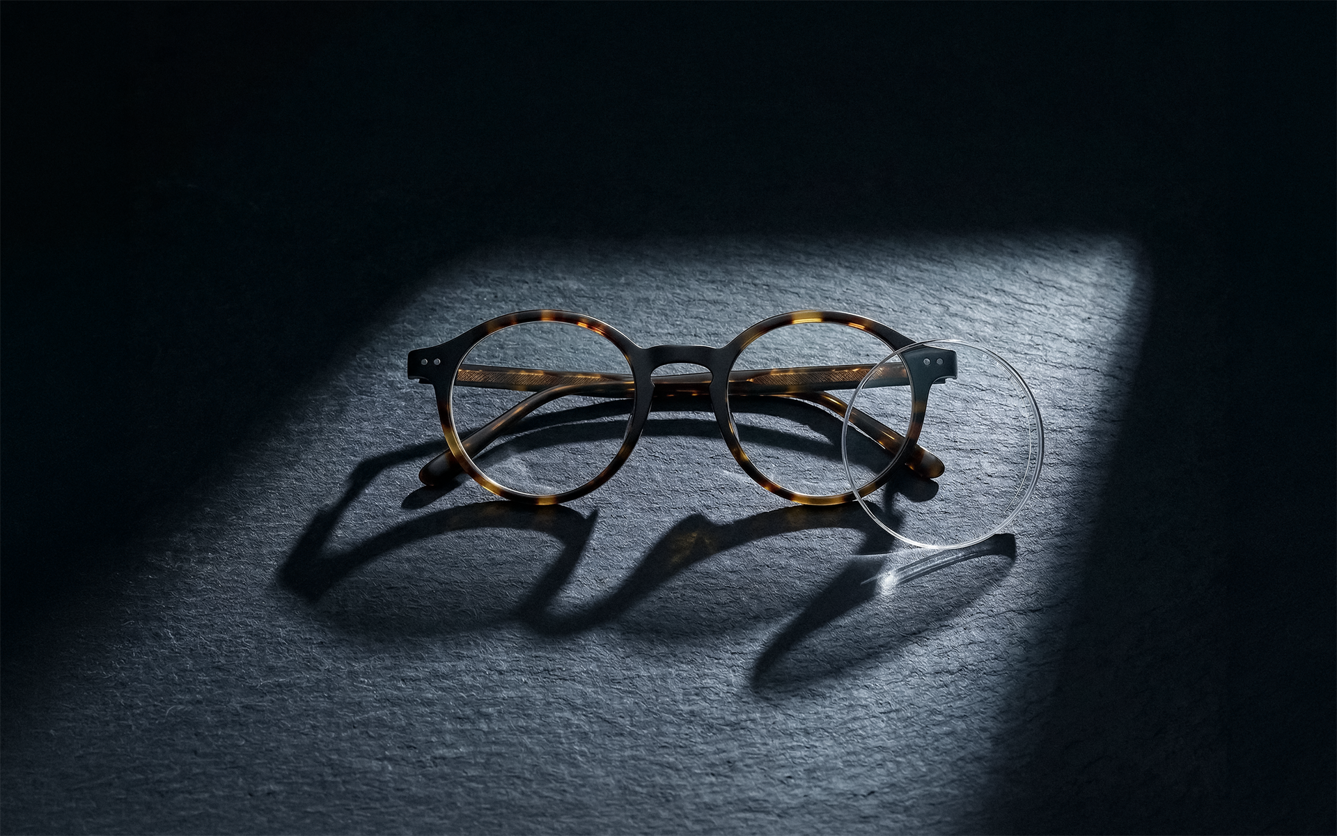 A hand holding a $100 hundred dollar bill against a teal background.