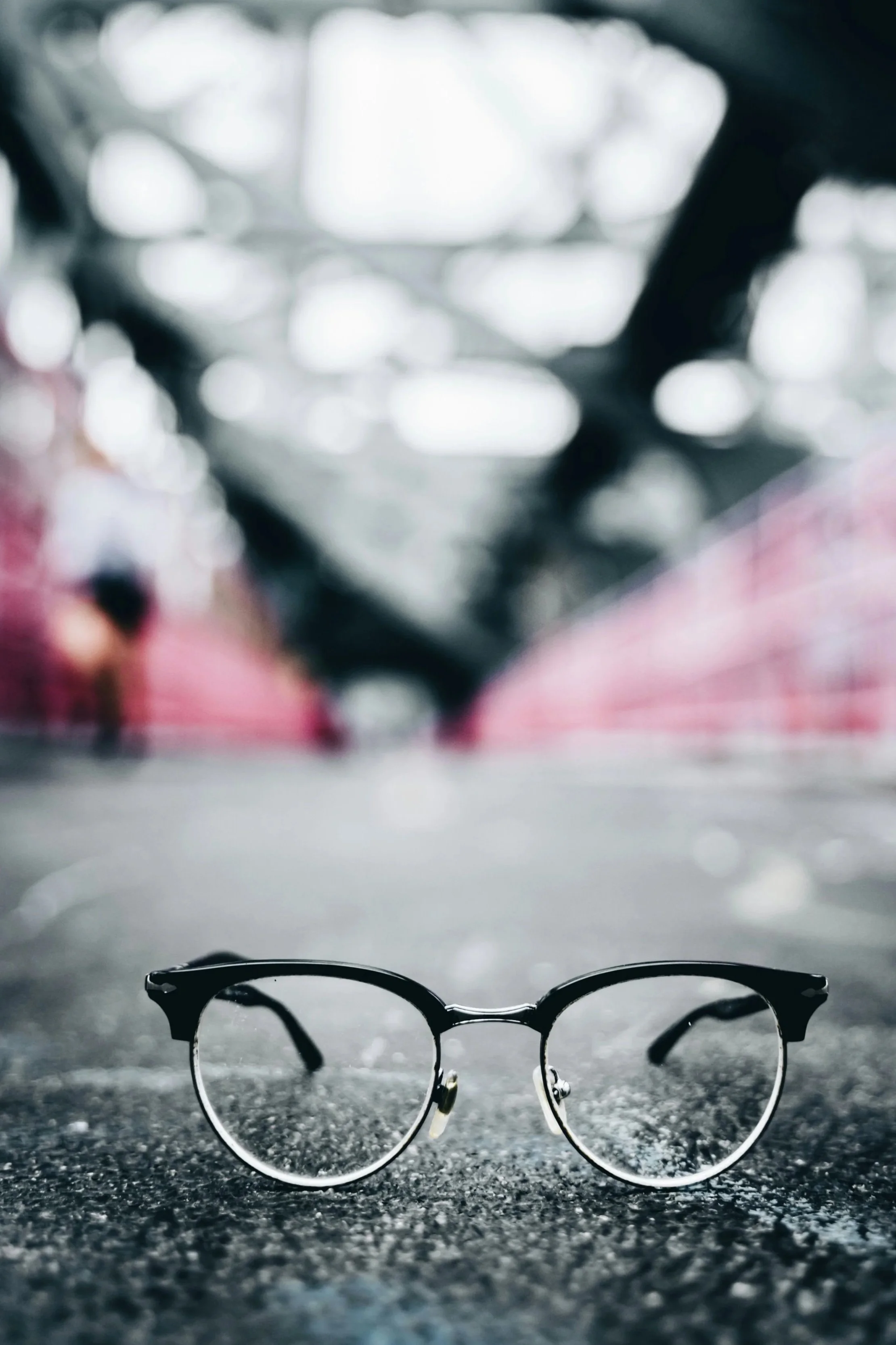 In focus black glasses with a blurry deep background with grey and red.