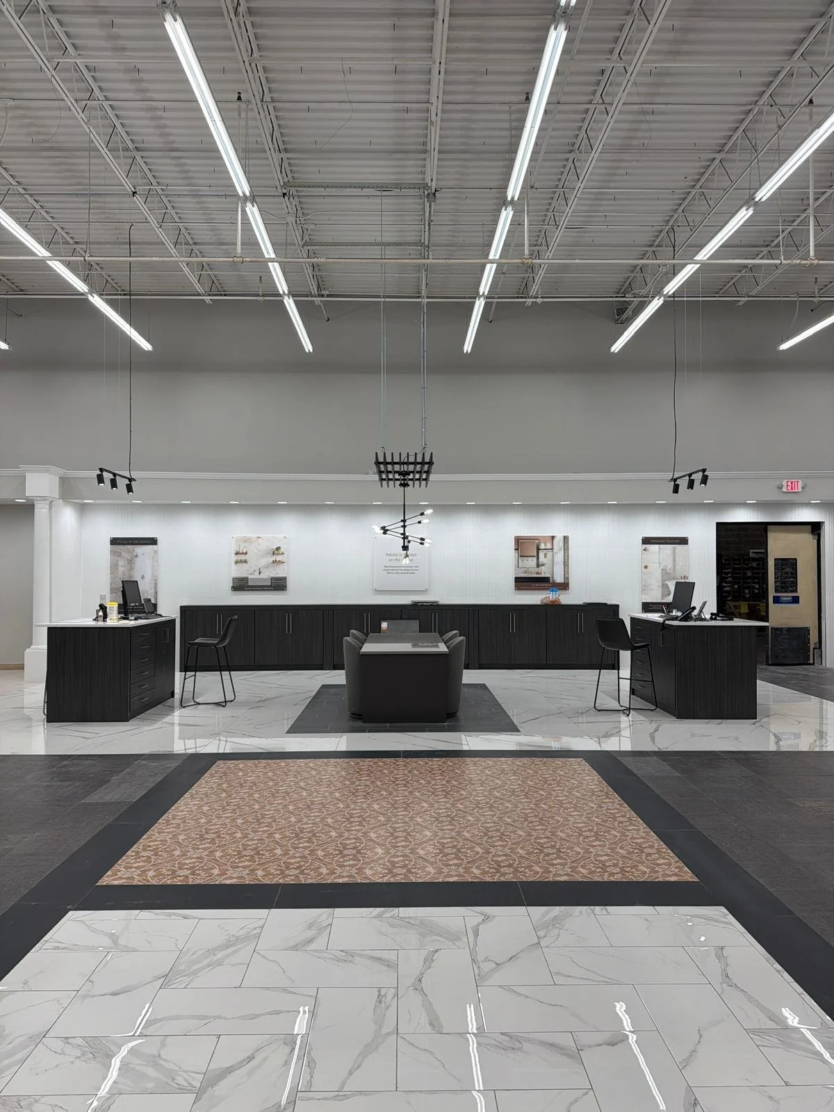 Empty reception area with black counters, computer stations, and modern lighting fixtures in a commercial building.