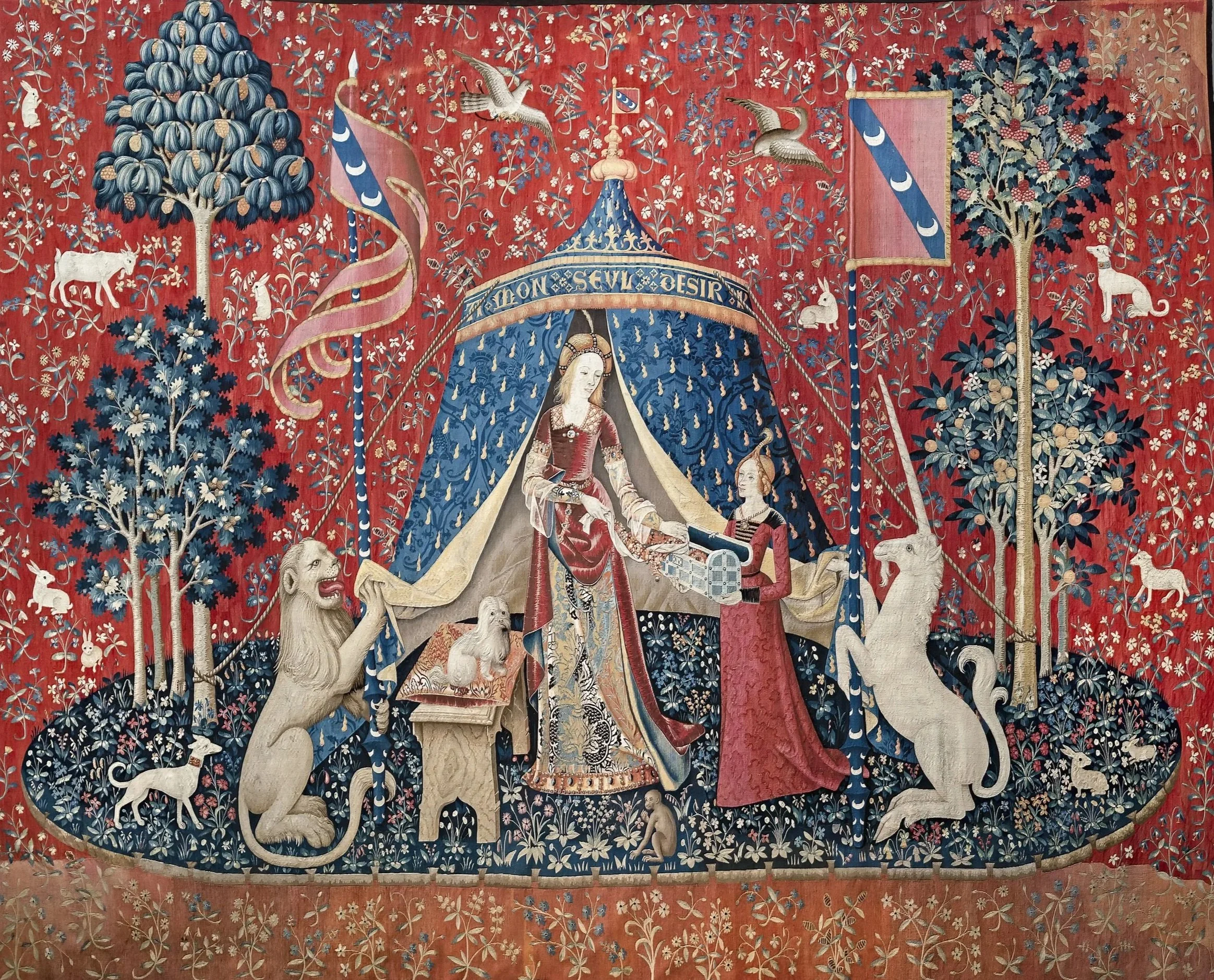 A tapestry depicting a medieval scene with a crowned woman seated under a canopy, handing a chest to a woman standing in front of her. The background features red fabric, trees, and various animals, including lions, wolves, and birds.