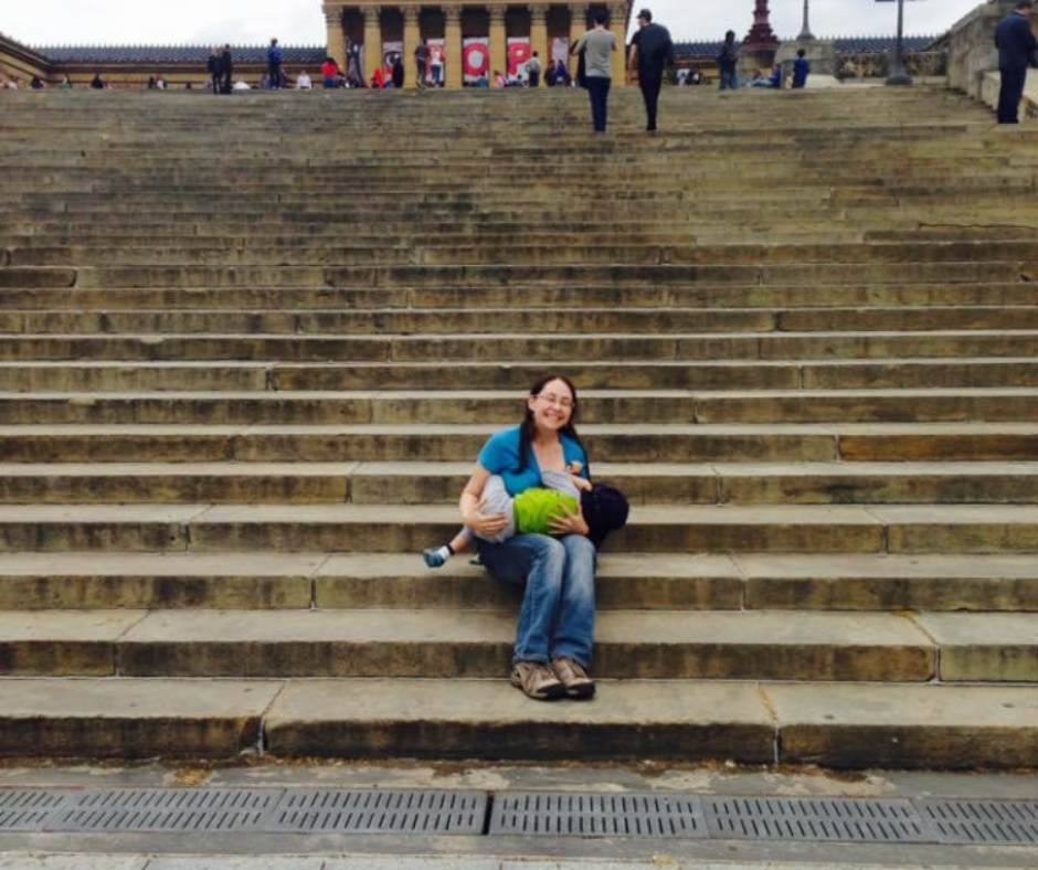 Woman sitting on the steps in front of the The iconic Rocky Steps are the 72 stone steps leading up to the Philadelphia Museum of Art. The woman is breastfeeding her 2-year-old son.