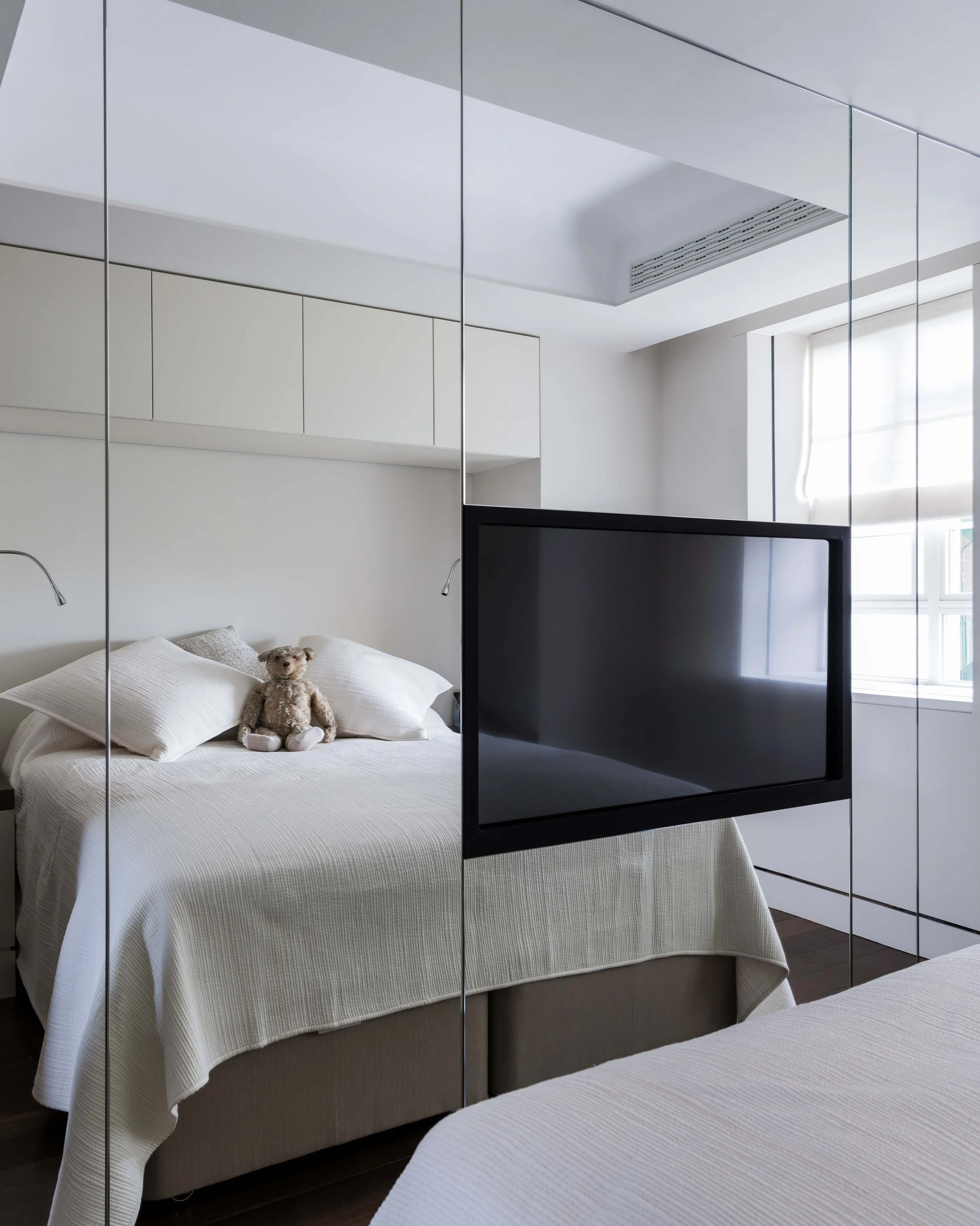 Custom mirror fronted wardrobe with built-in TV, crafted by NBJ