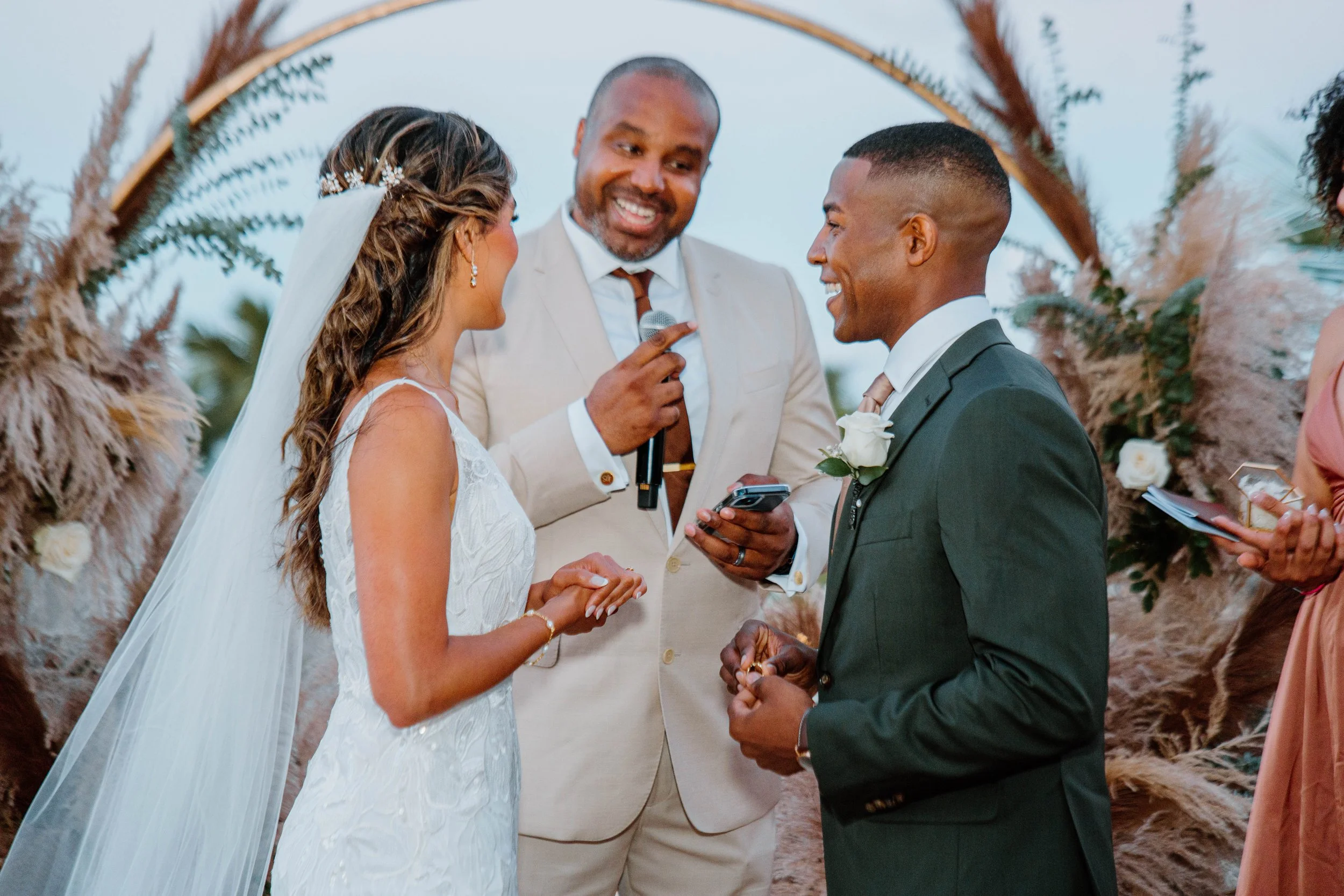 Bride and groom exchanging vows with officiant at an outdoor wedding ceremony.