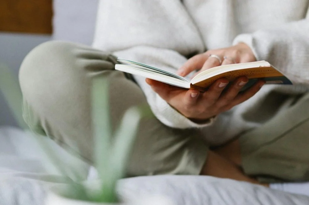 person sitting crossed legged holding an open book