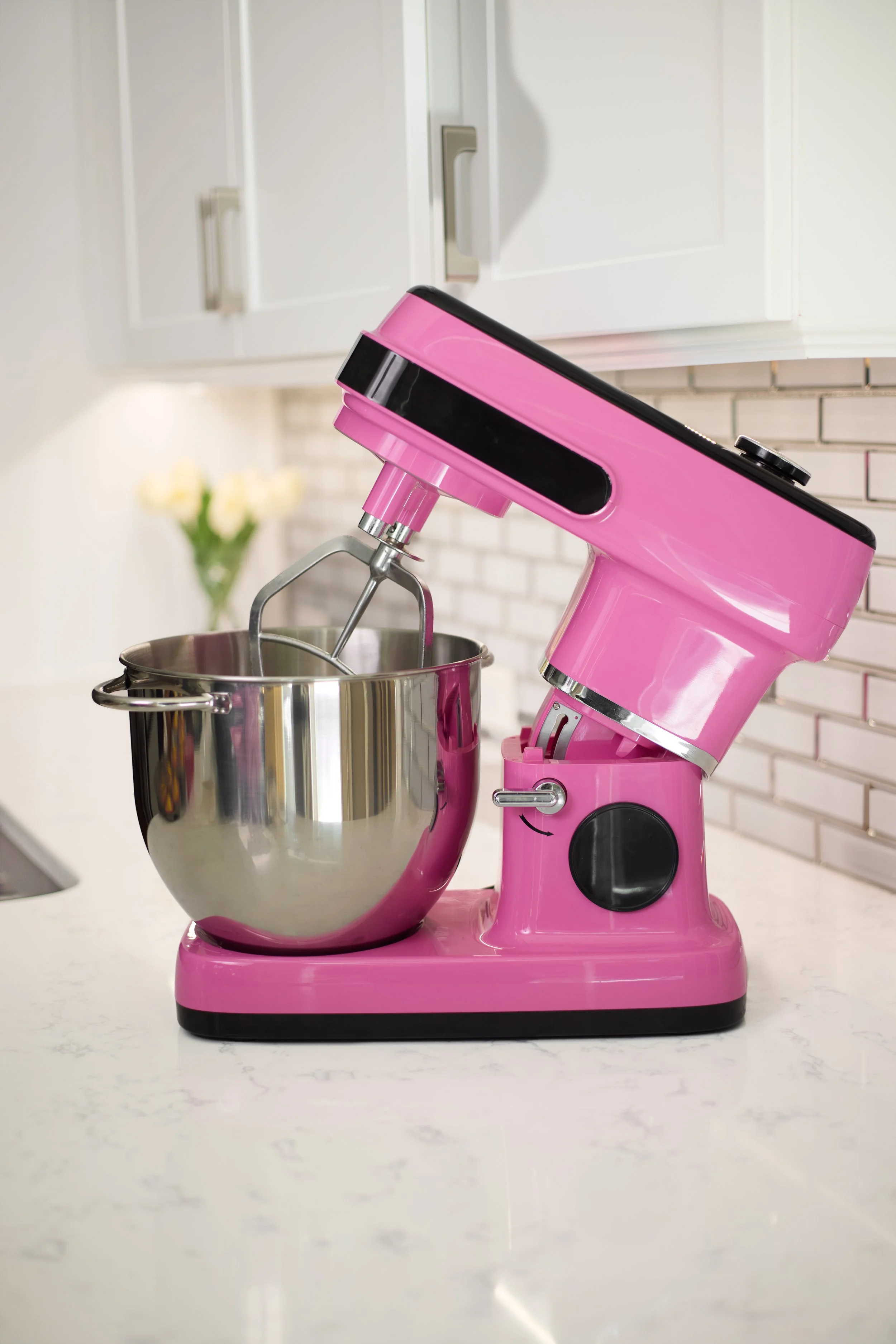 Pink stand mixer with metal mixing bowl on a kitchen countertop.