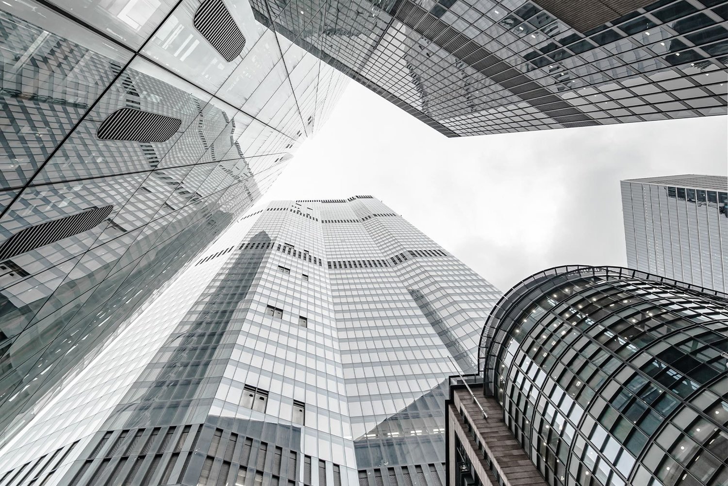Looking up at modern skyscrapers with glass facades in an urban city.