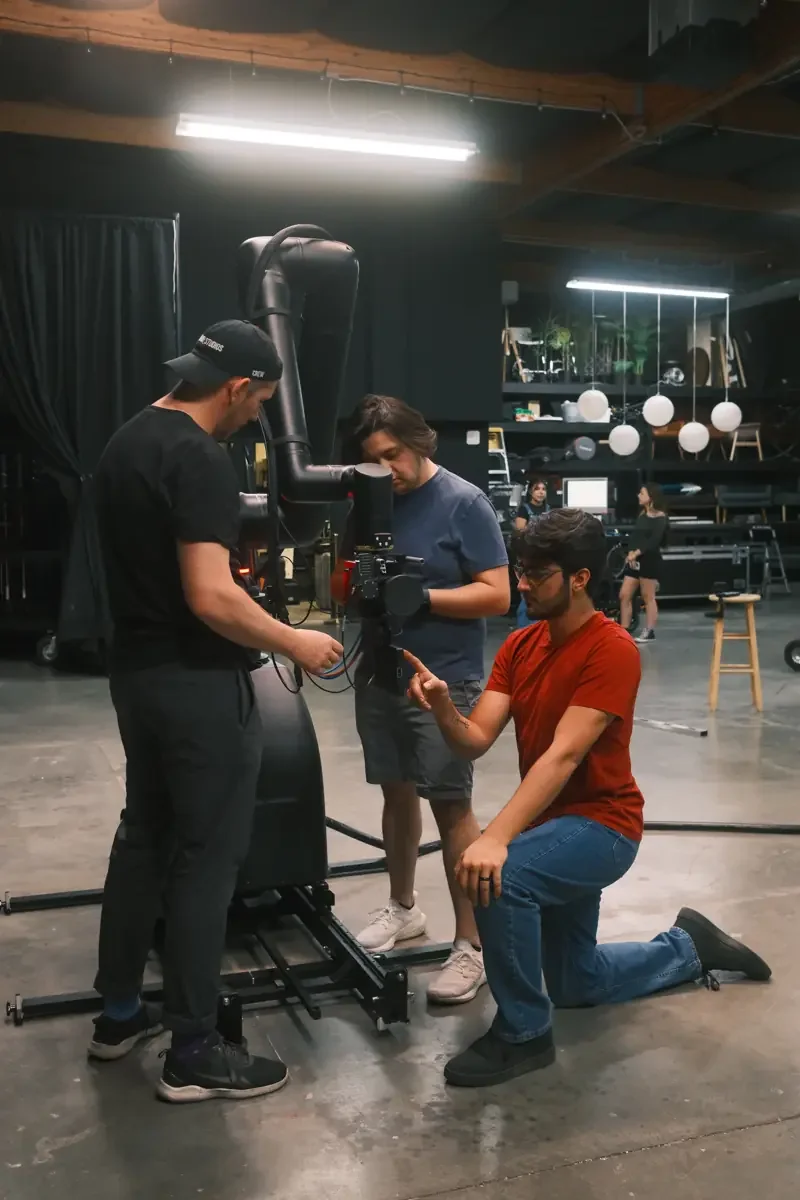 Production crew setting up a cinema camera on a robotic arm in the studio