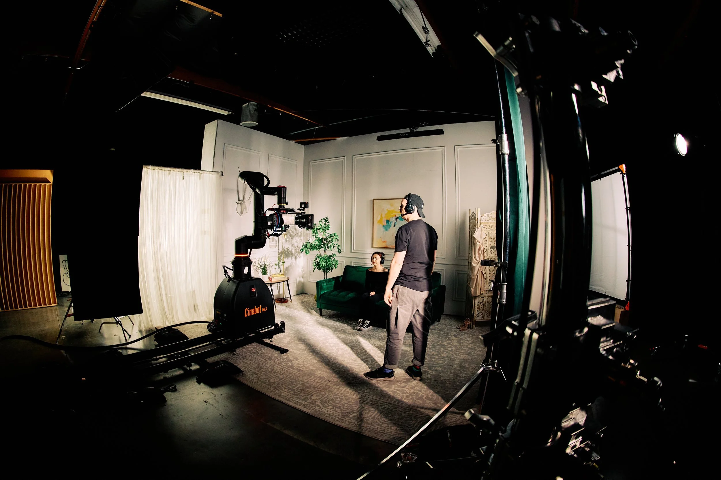Cinebot Max on track in a dressed interior set with a performer, crew and lighting.