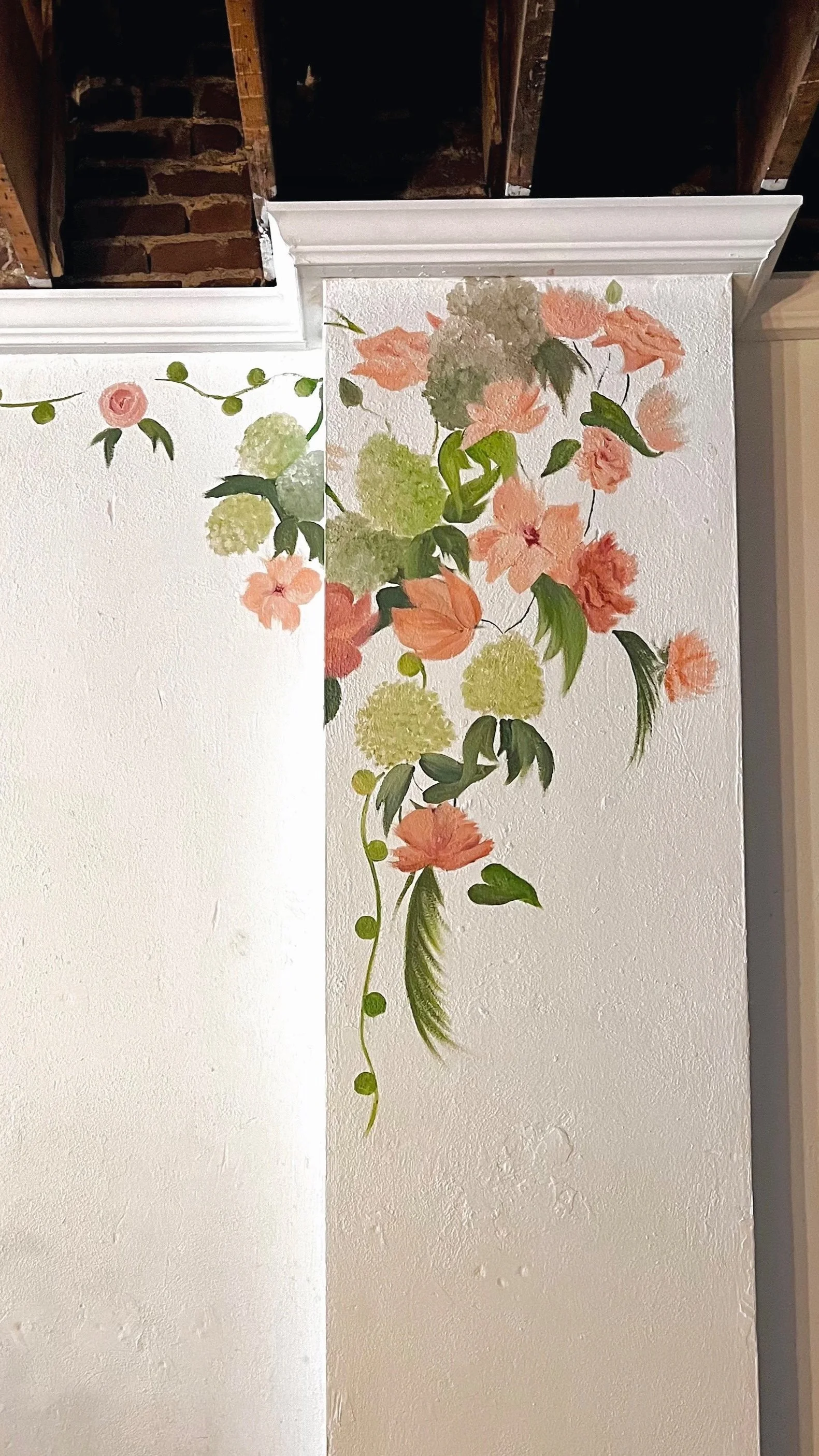 A wall with floral watercolor mural of pink and green flowers and leaves.