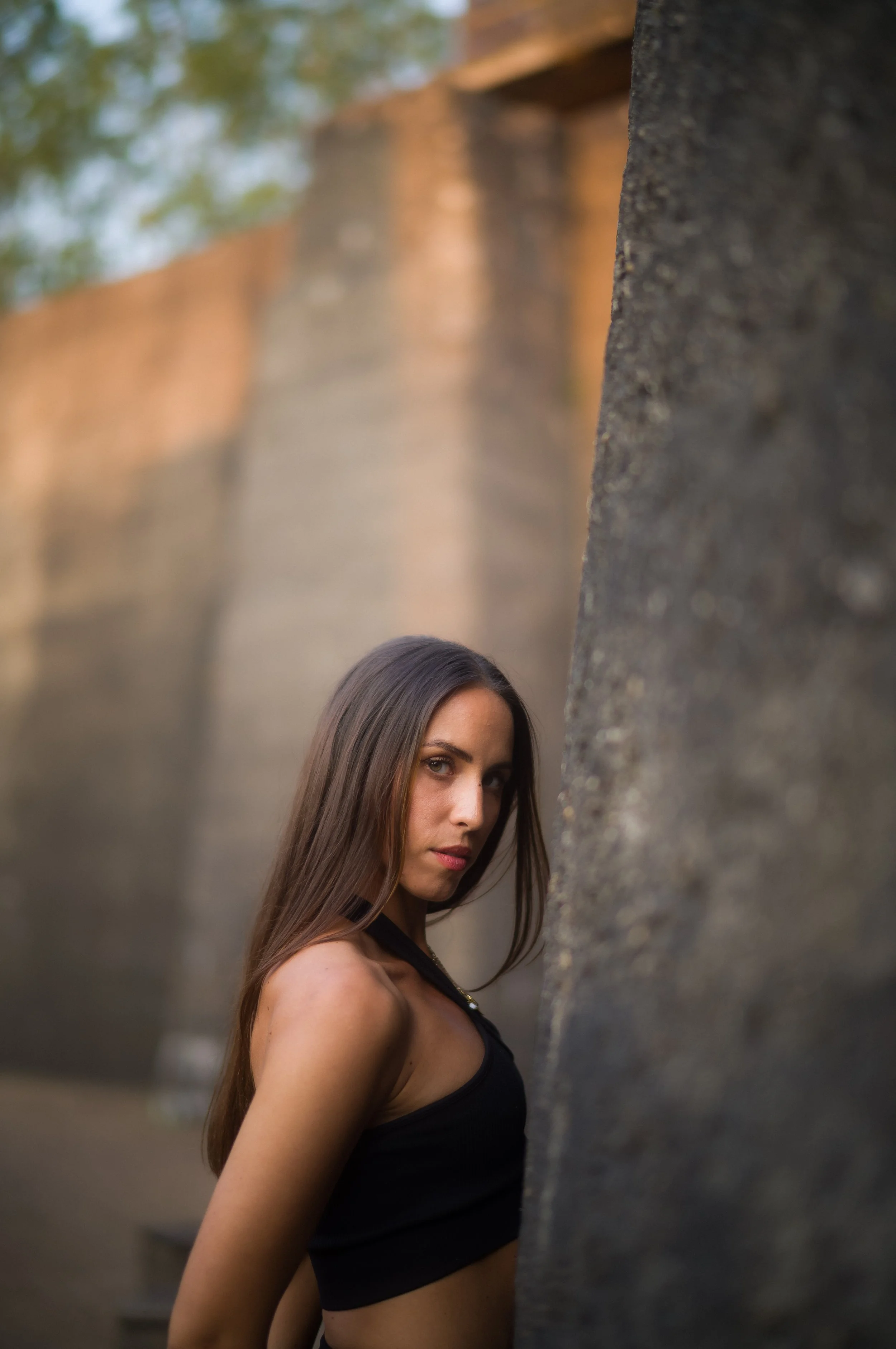 Künstlerin im Fotoshooting, seitliche Pose mit ernstem Ausdruck, Arme hinter dem Rücken verschränkt.