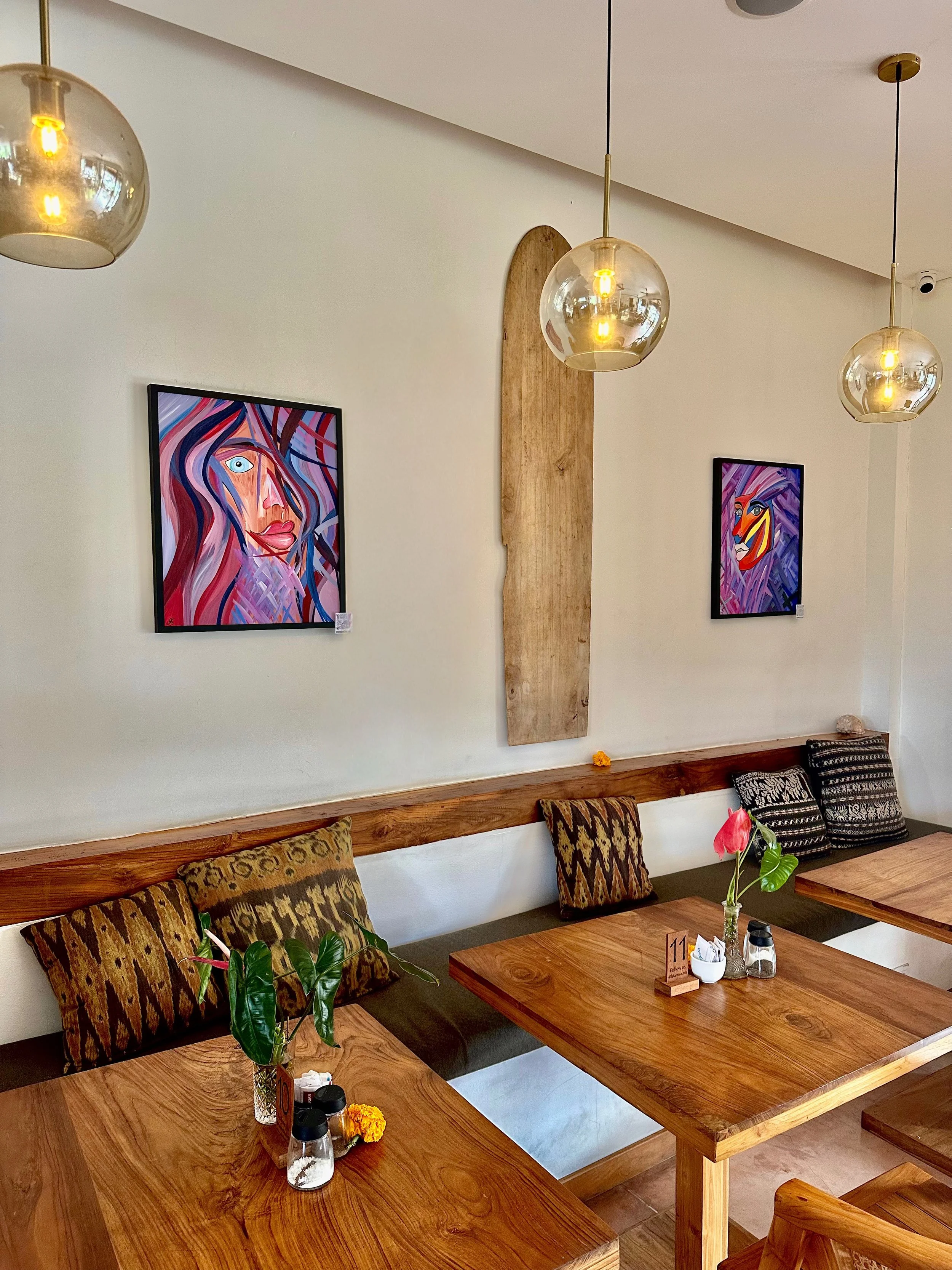 Ausstellungsszene im Restaurant La Kantina in Uluwatu, Bali, mit den Werken „Soul Fire“ und „Silent Beauty“ an der Wand präsentiert.